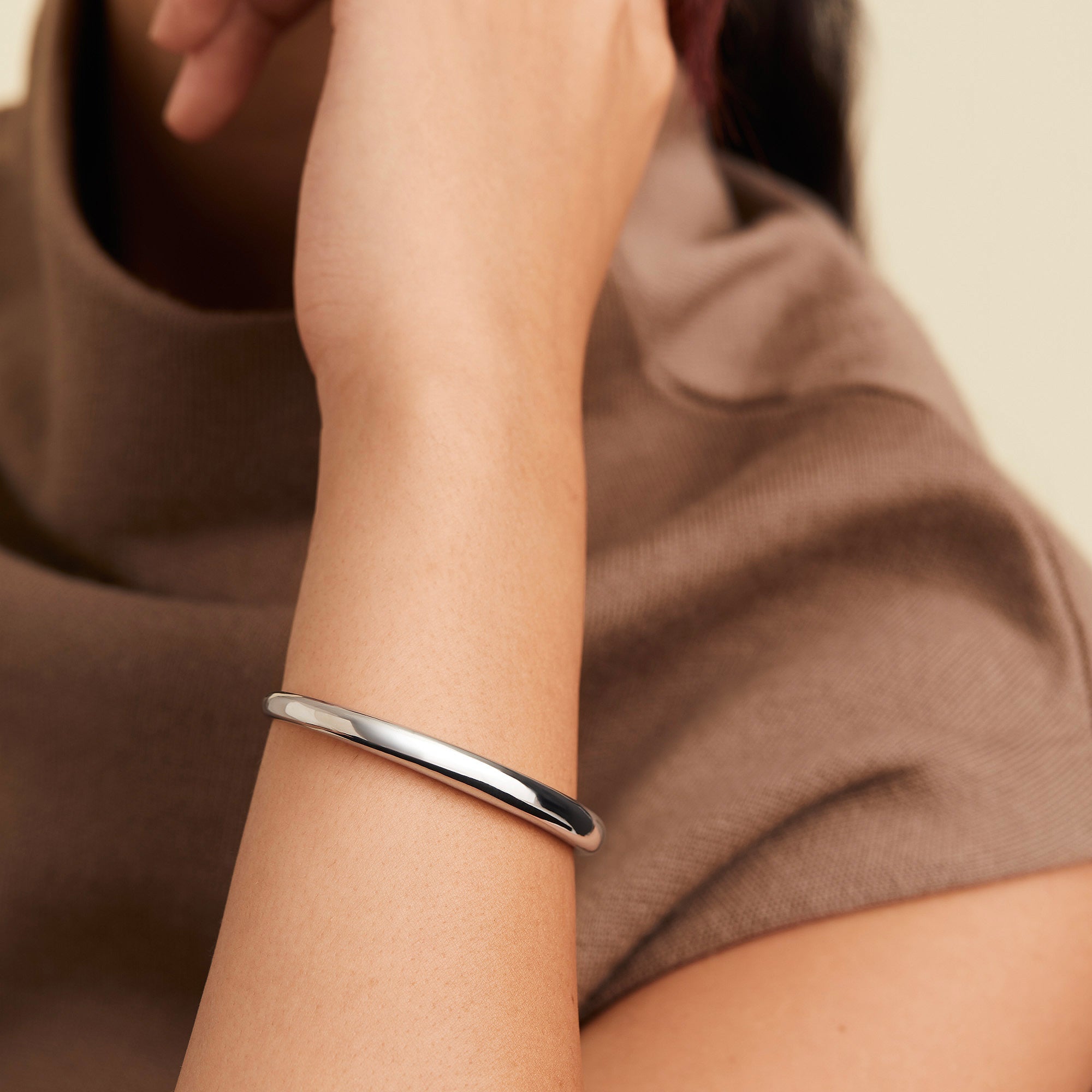 A close-up of a person wearing the DÃ´me Cuff Bracelet, a silver fashion accessory inspired by a ray of sunshine, elegantly wrapped around the wrist.
