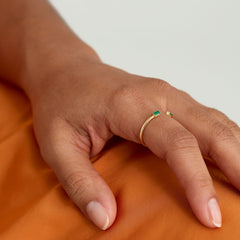 Baguette Emerald Open Ring on a hand, featuring a gold band with a green gem, highlighting its tapered baguette design and handcrafted precision.