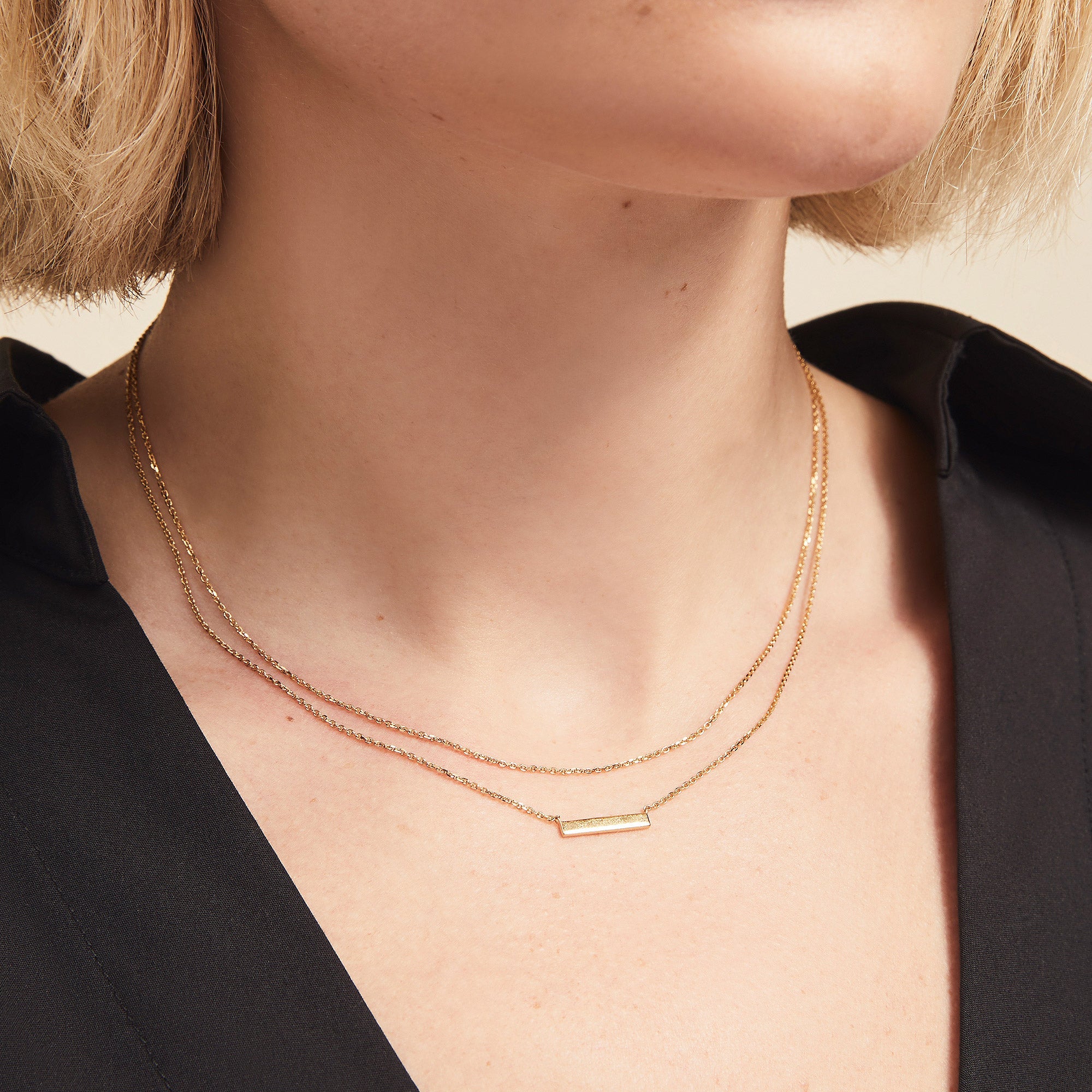 Woman wearing the Layered Bar Necklace, a versatile fashion accessory showcased elegantly around her neck, highlighting its layered design for everyday wear.