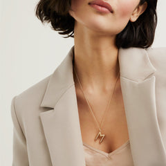 Woman wearing Bold Letter Pendant Necklace in 18k gold vermeil with an accordion pattern on a 20 to 22-inch cable chain.