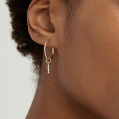 Close-up of a woman's ear adorned with a Single Diamond Icicle Hoop Charm, highlighting the elegant, personalized addition to everyday hoop earrings.