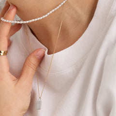 Pave Diamond Bail Tag Charm Pendant worn by a person, showcasing a 14k gold pendant with a pavÃ© diamond-set bail, highlighting its elegance and craftsmanship.