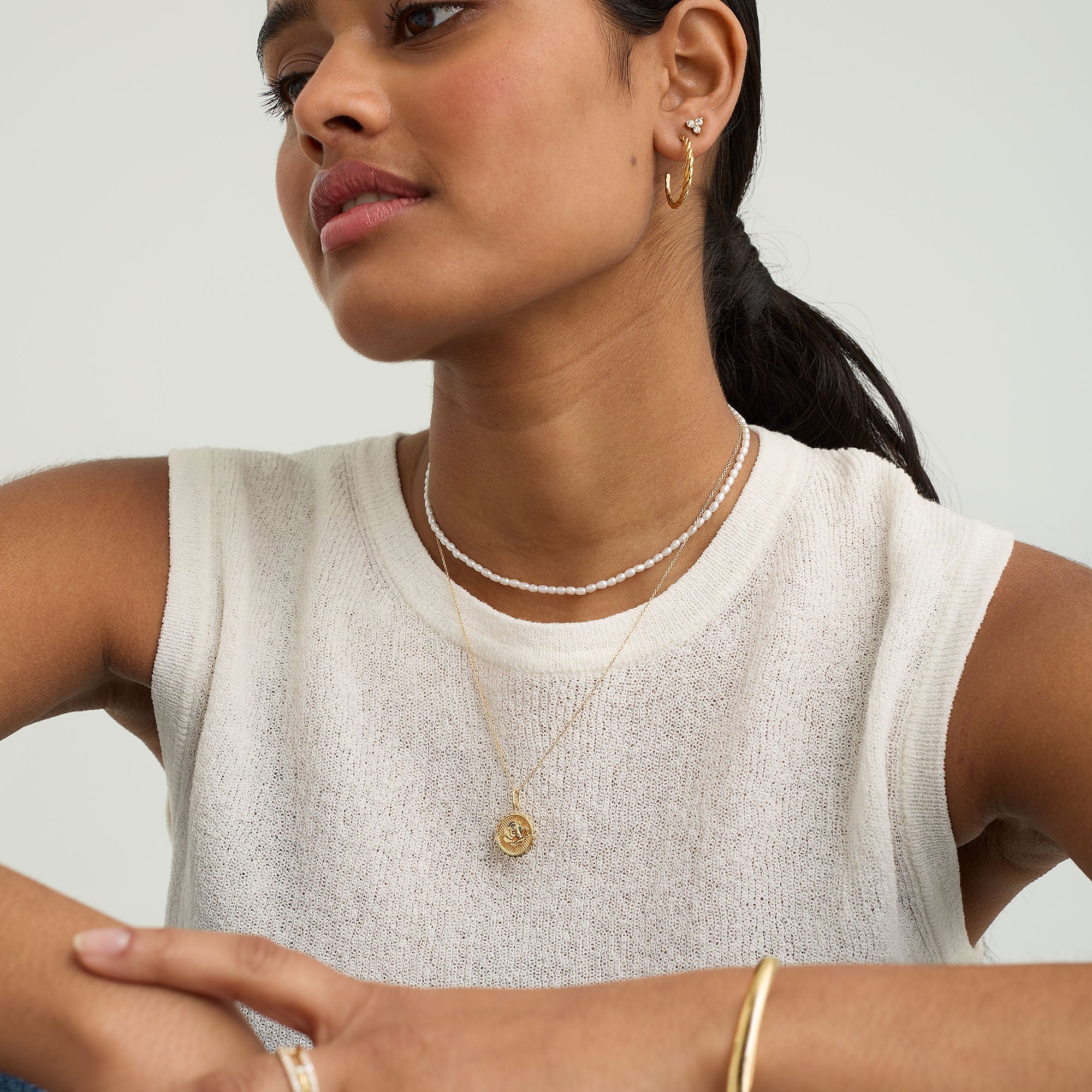 Woman wearing a white shirt and the Strength: Rose Coin Charm Pendant in recycled 14k solid gold, symbolizing strength and new possibilities.