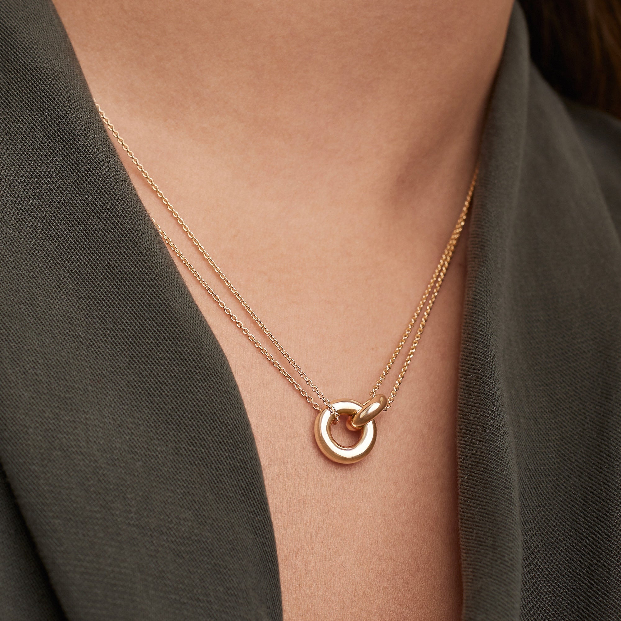 Person wearing Vermeil Linked Necklace featuring two interlinked rings, symbolizing strong personal bonds. Handcrafted in gold vermeil over 925 sterling silver.