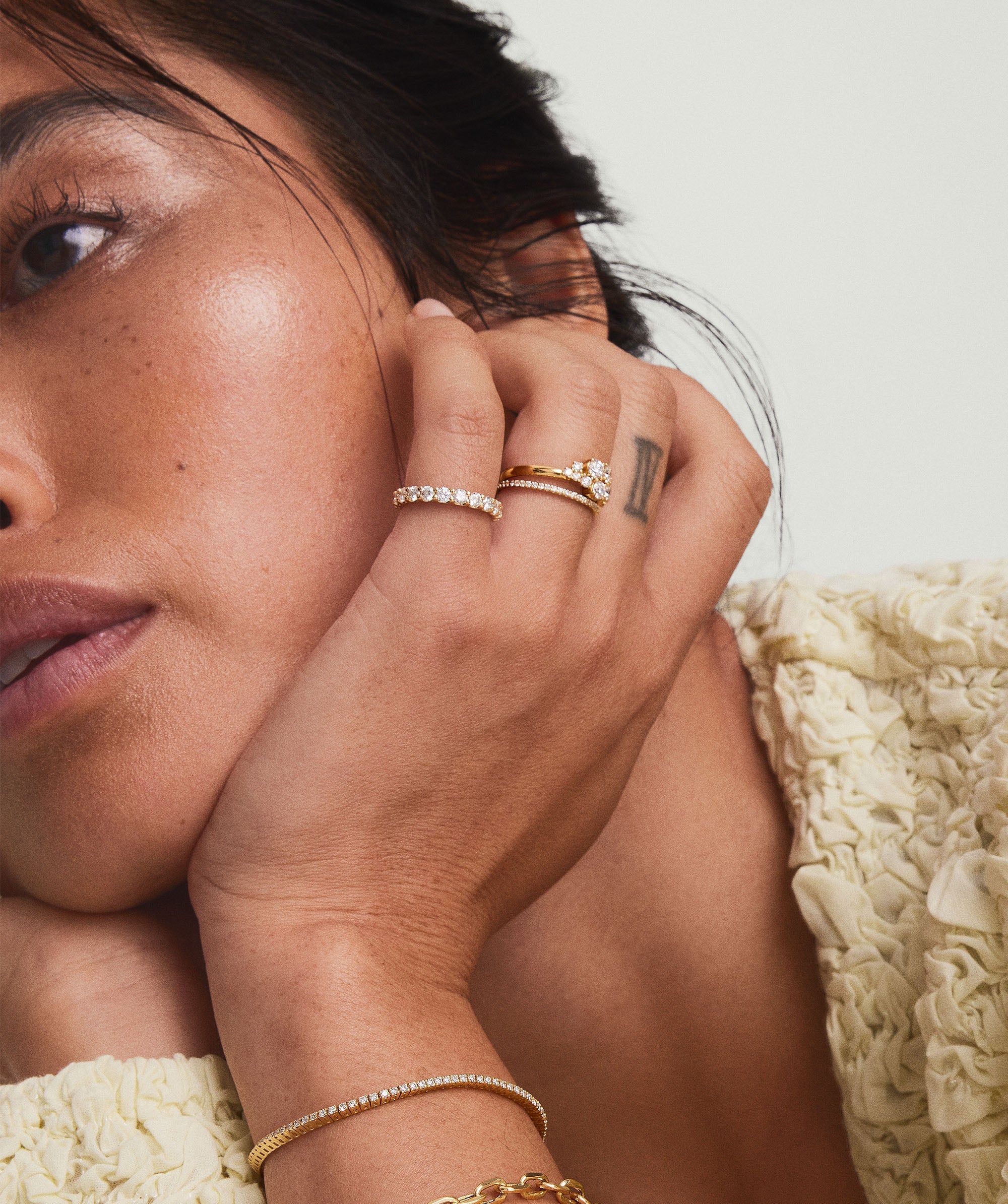 Woman showcasing the Diamonds Cluster Ring with eleven diamonds in prong settings, hands near her face, highlighting the ring's asymmetric and organic design.