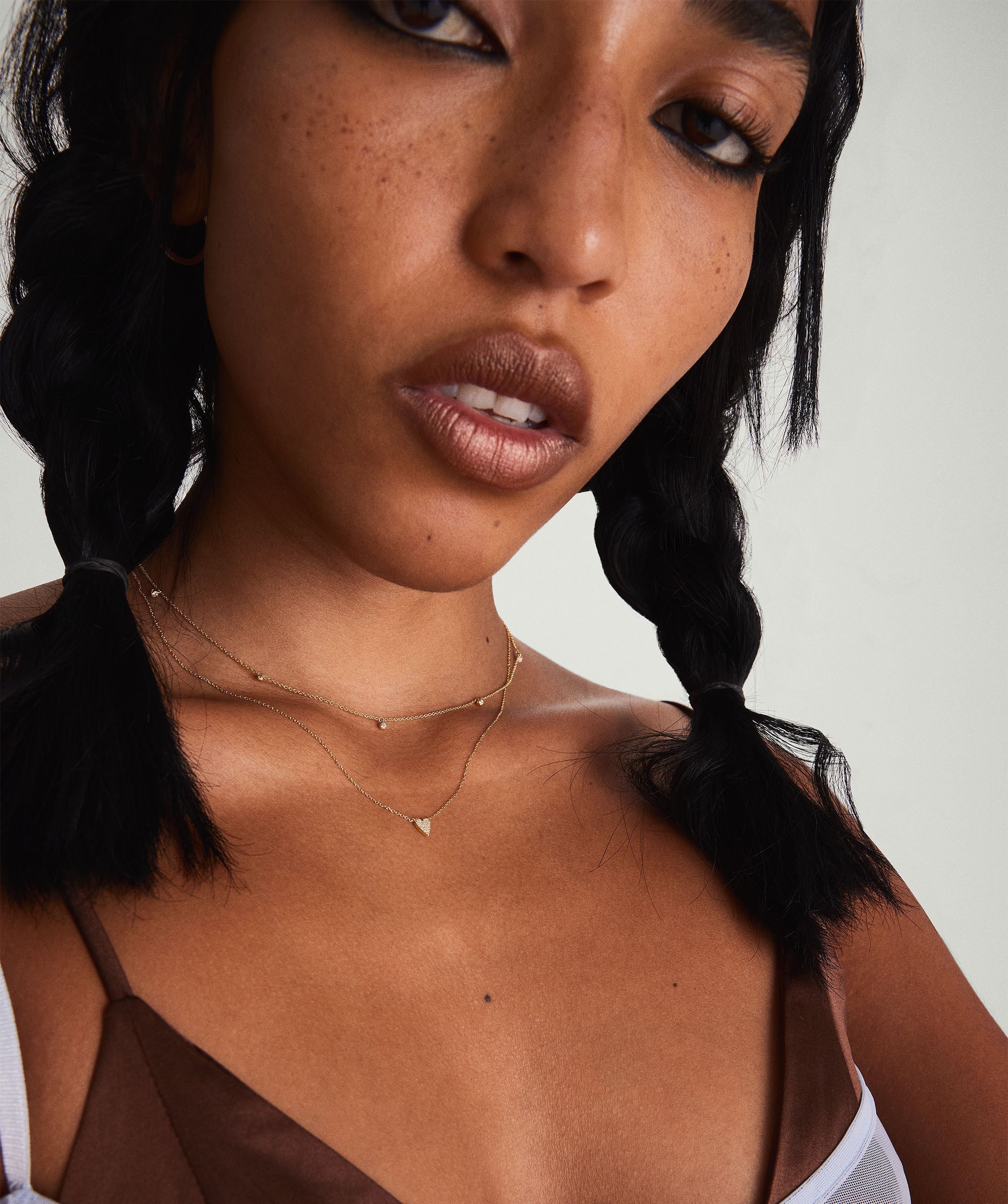 A woman with braids wearing a Mini Heart PavÃ© Diamond Necklace, posing for a close-up photo.