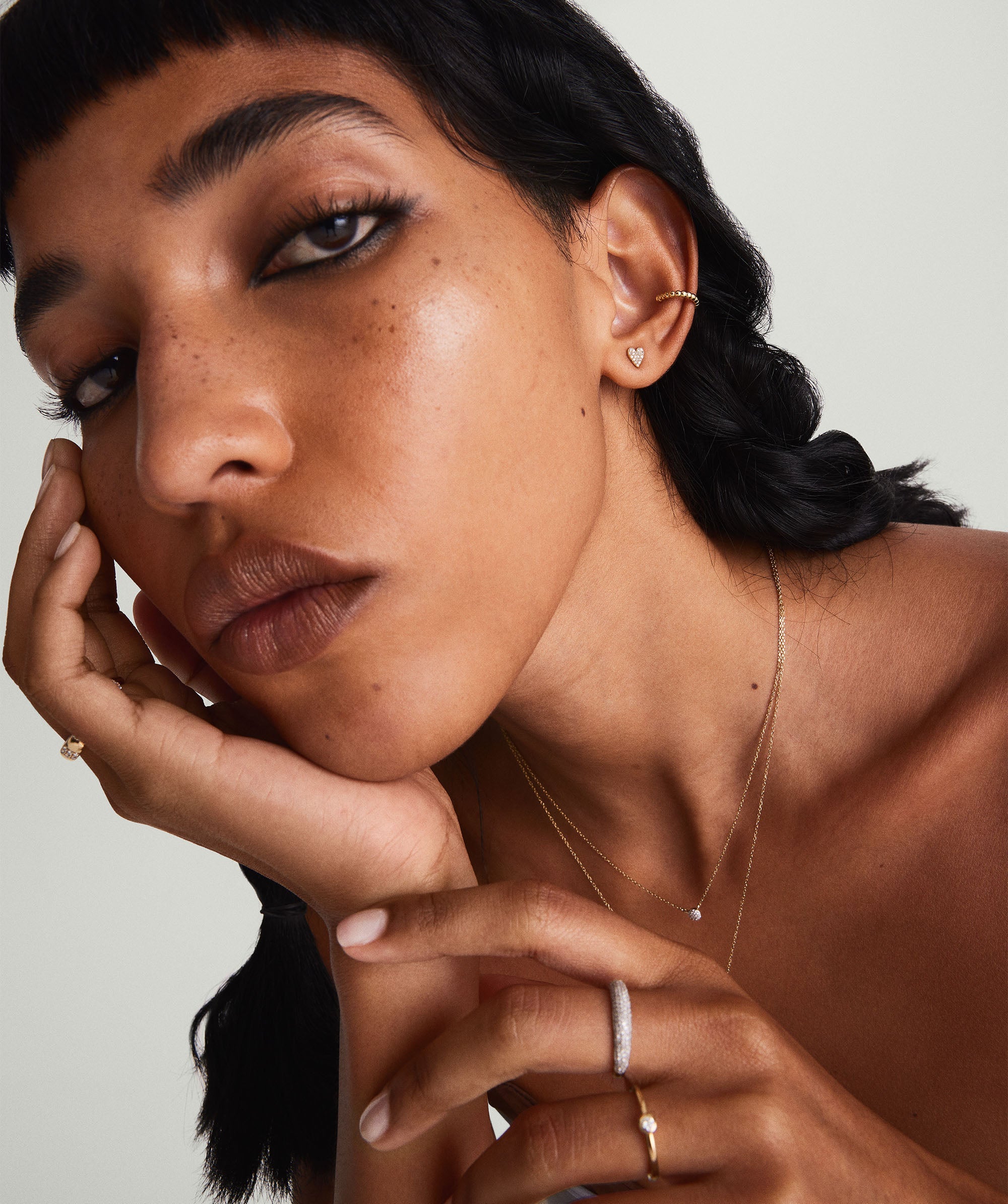 Close-up of a woman wearing Mini Heart PavÃ© Diamond Stud Earrings, emphasizing their handcrafted 14k solid gold design and sparkling pavÃ© diamonds.