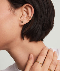 Close-up of a woman's ear wearing a handcrafted 14k solid gold Letter Stud earring.