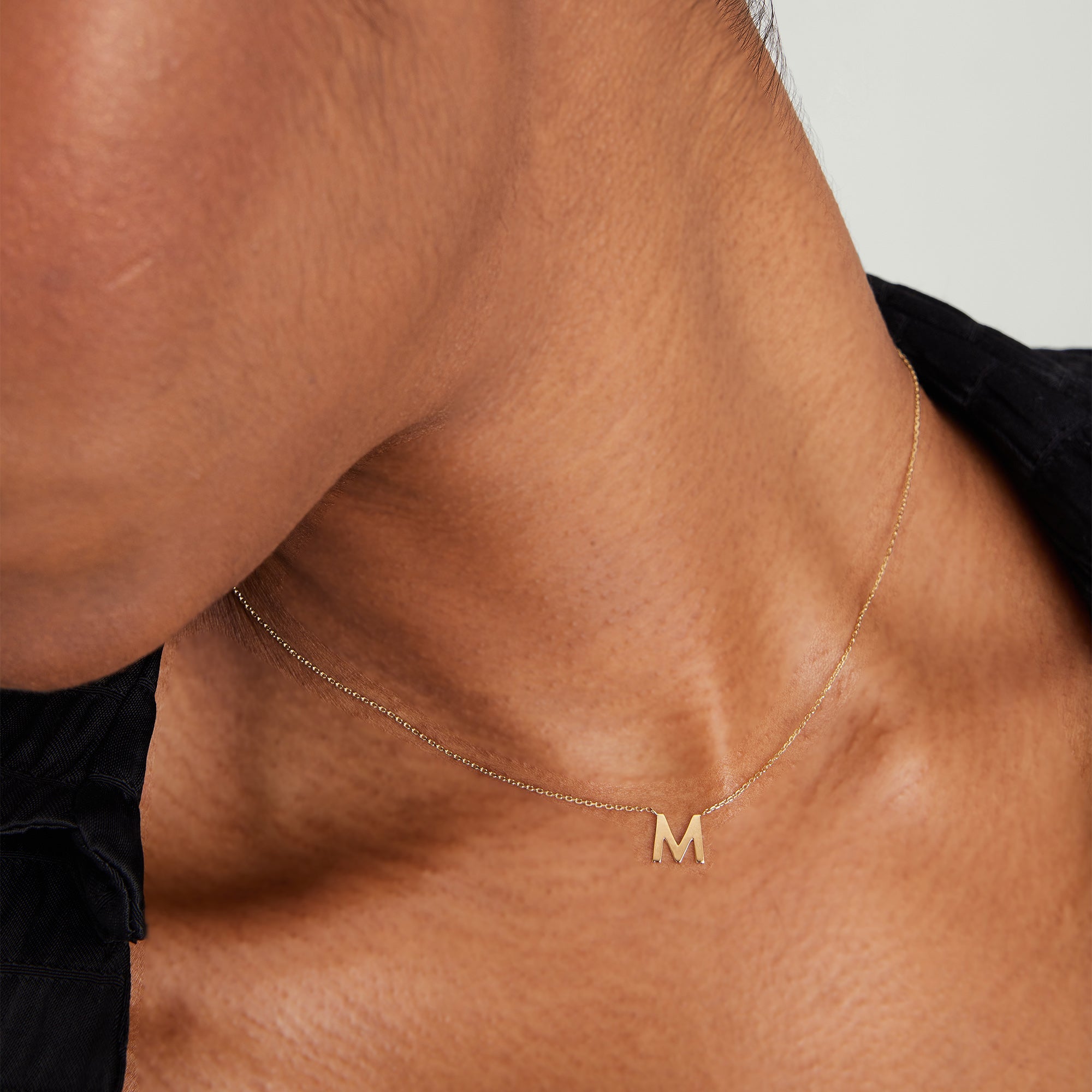 Person wearing a gold letter necklace on a chain, showcasing the elegant design of the Letter Necklace, a must-have fashion accessory for any jewelry collection.