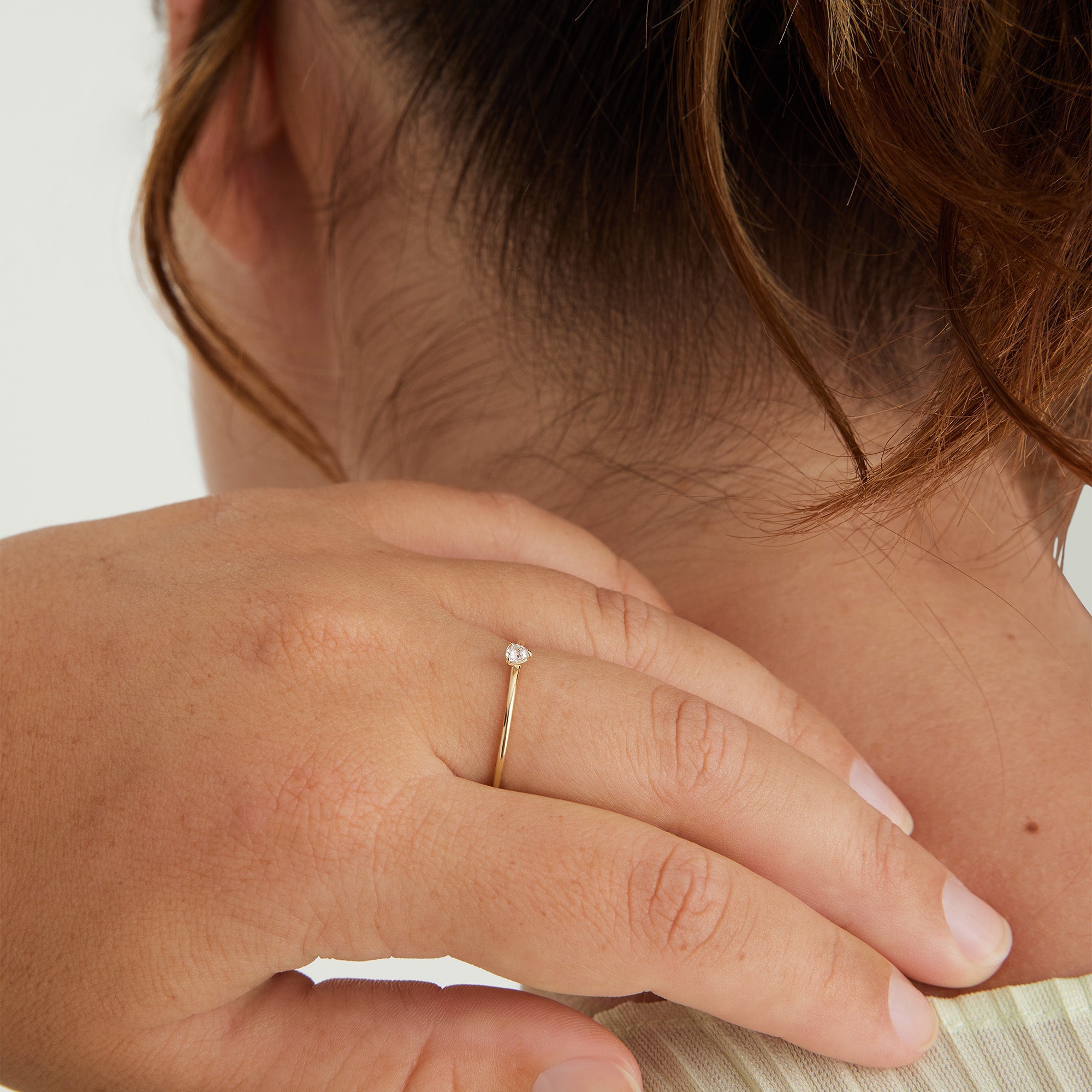 Close-up of a hand wearing the Gemstone Trillion Stacker Ring, featuring a white topaz gemstone set in 14k solid gold.