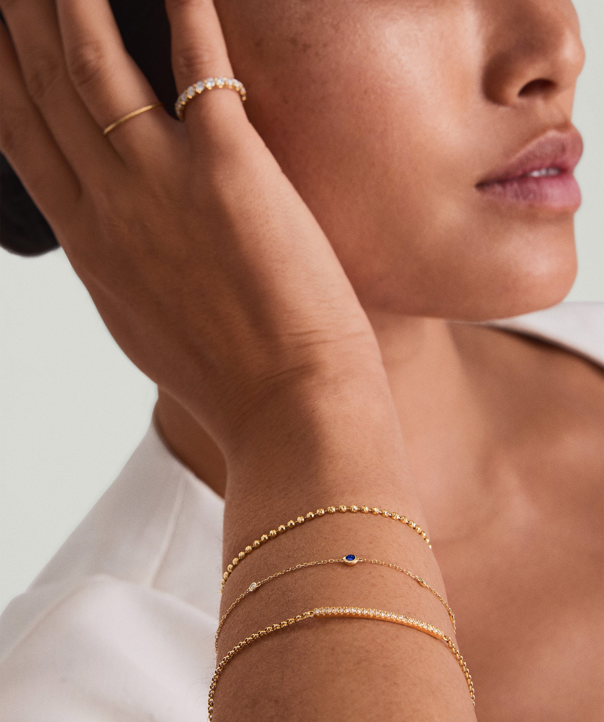 Woman wearing Multi Gemstone Station Bracelet in 14k gold, showcasing intricate, colorful gems. Close-up highlights the bracelet's elegant design and craftsmanship.