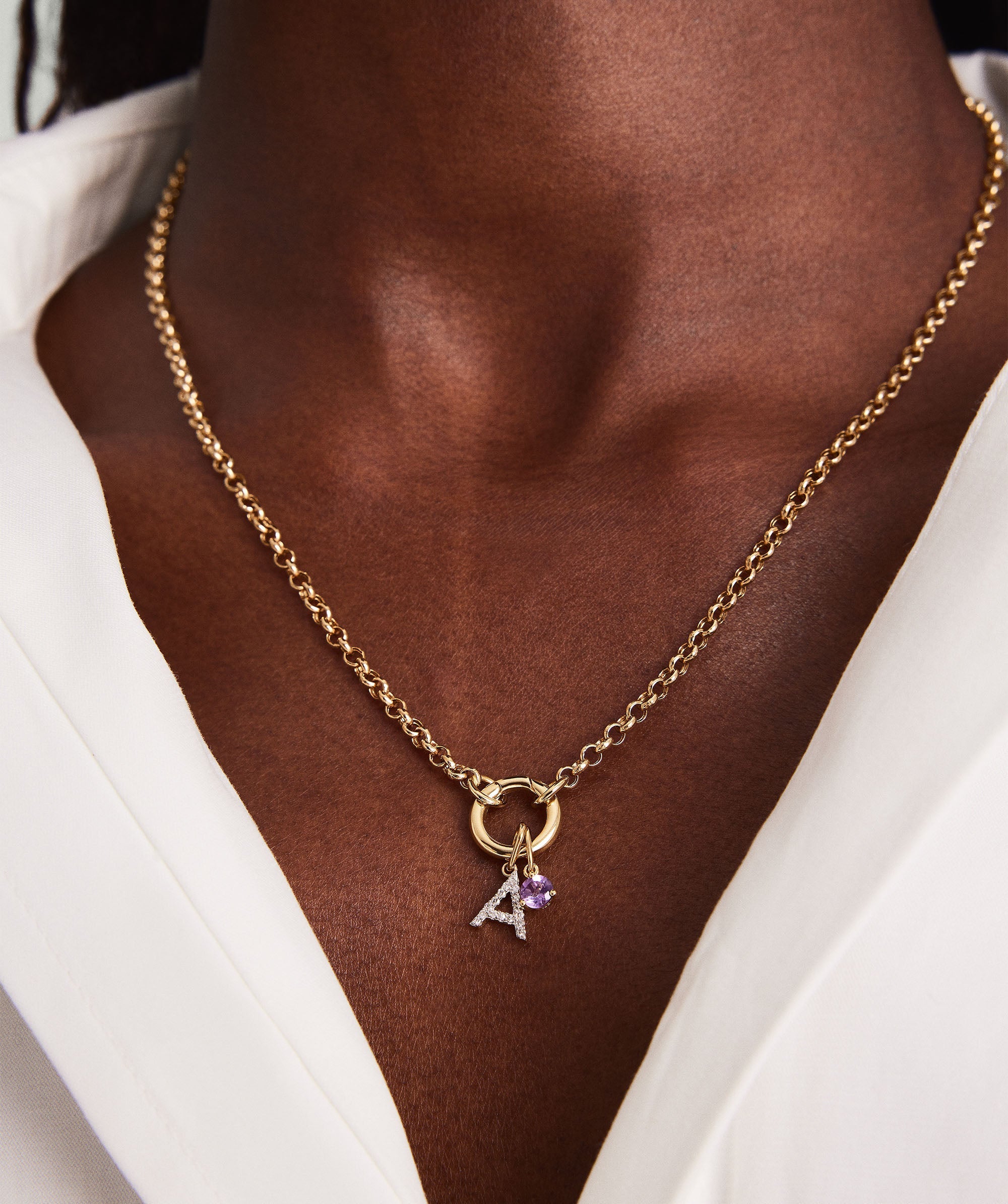 Person wearing a Birthstone Charm necklace, handcrafted in 14k gold with a gemstone pendant, close-up on the chest area.