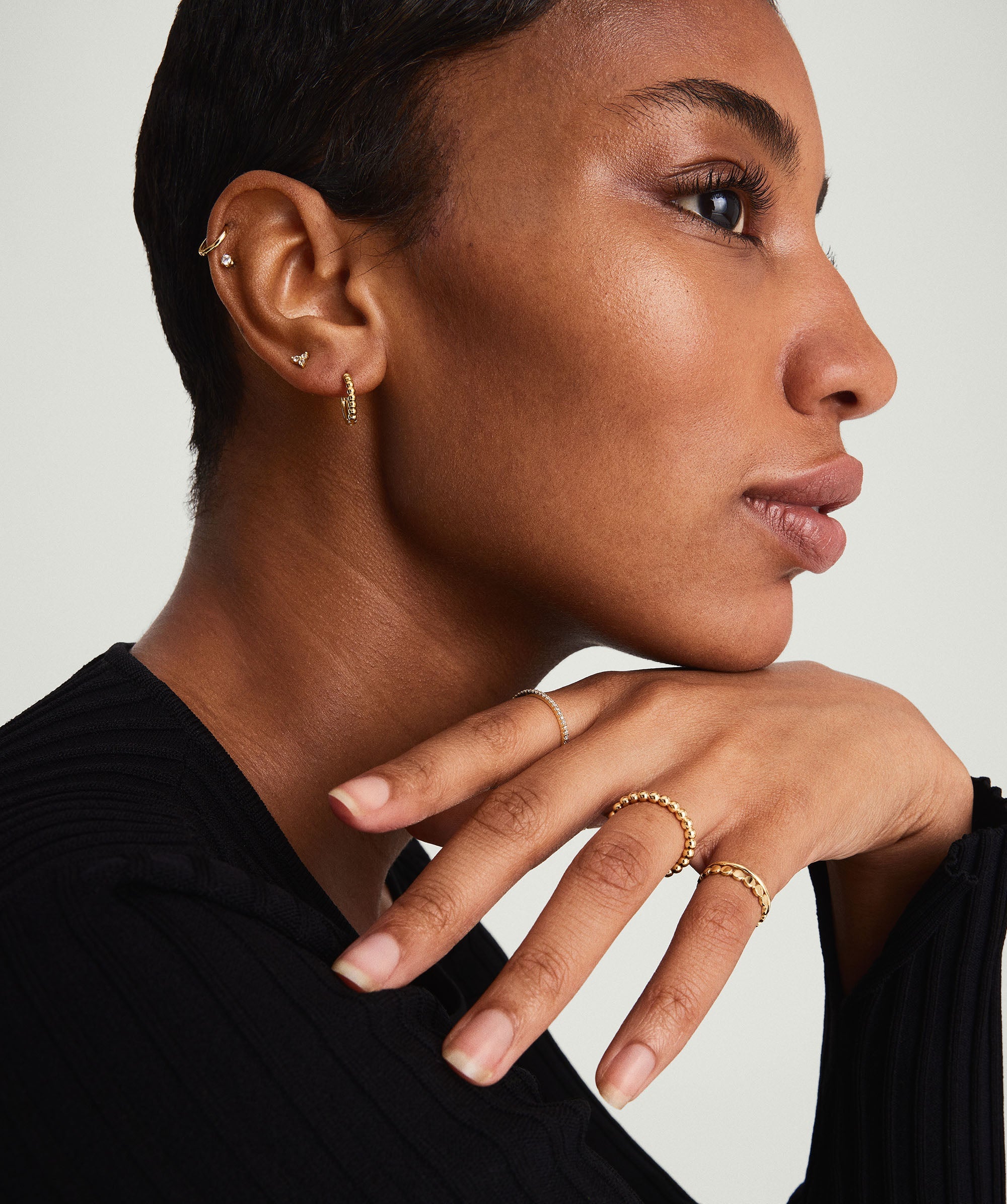 Beaded Huggie Hoops showcased on a woman with short hair, highlighting handcrafted, recycled 14k solid gold jewelry in a close-up of her ear.