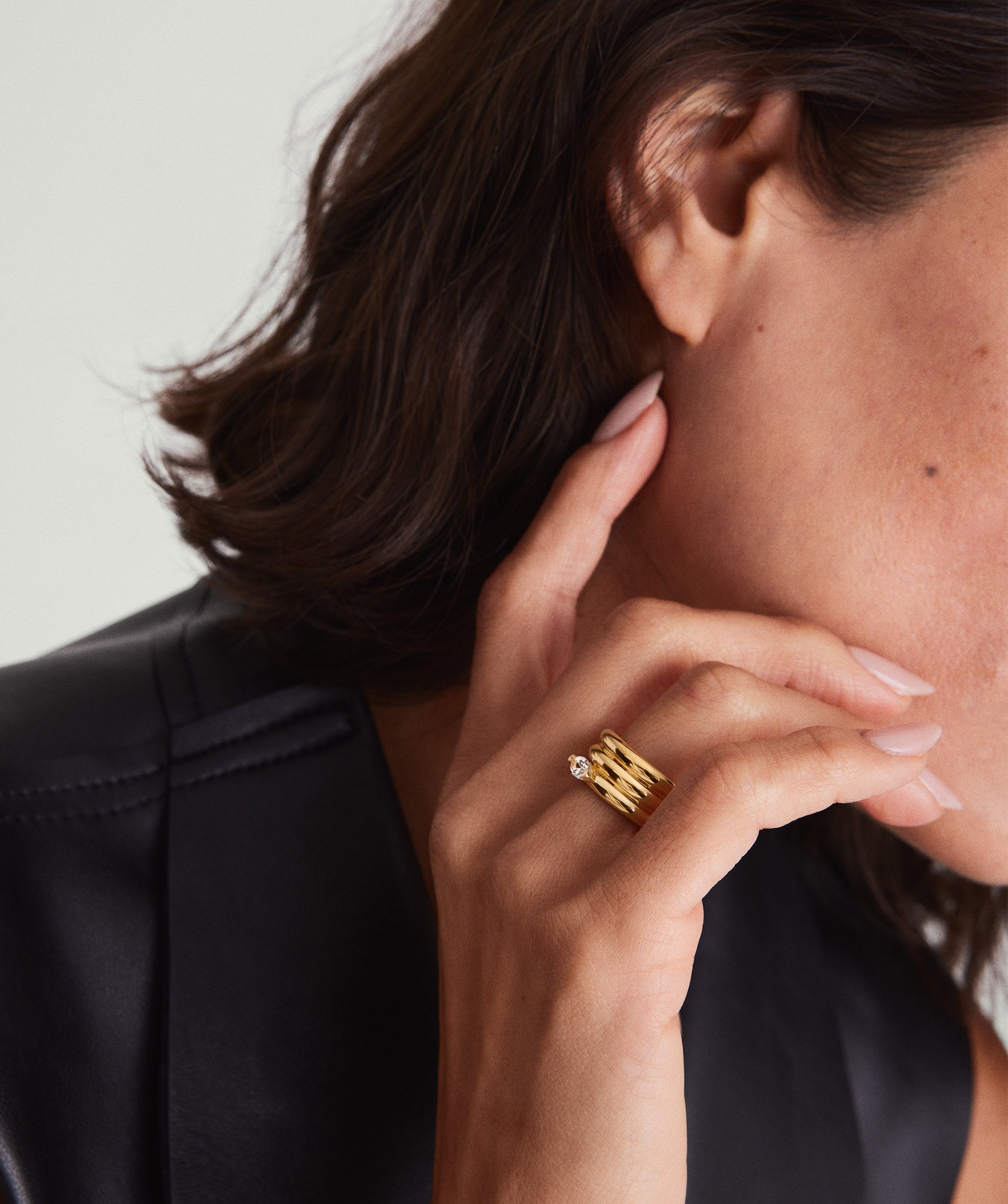 Close-up of a woman's hand wearing the Boa Gemstone Coil Ring, featuring a gold band and a prominent diamond detail.