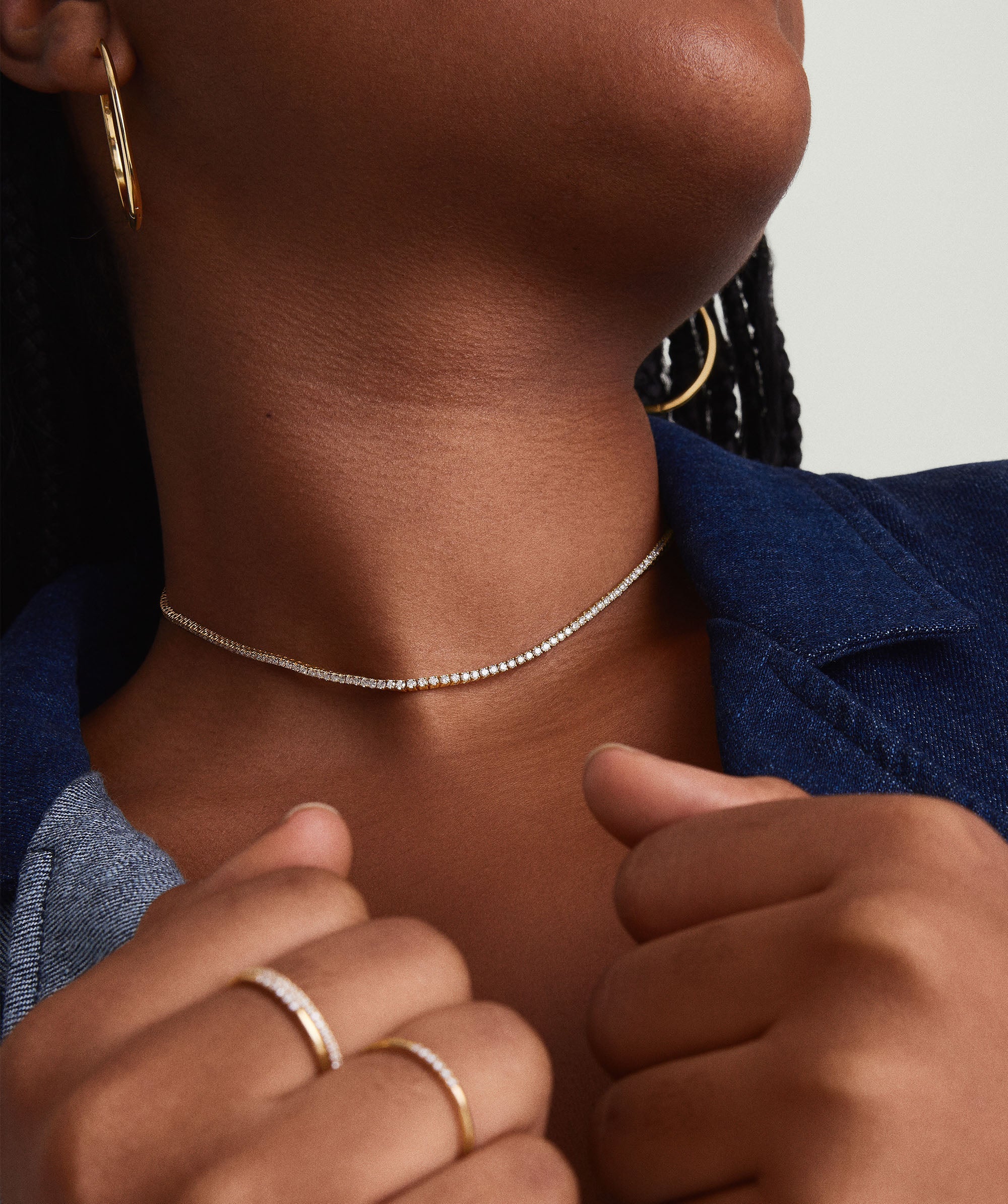 Close-up of a woman wearing a Diamond Tennis Necklace 1.8mm, featuring handcrafted 14k solid gold with responsibly sourced diamonds, and matching gold earrings.