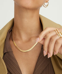 Close-up of a woman's neck wearing the Bold Herringbone Chain Necklace, showcasing its intricate design as a stylish fashion accessory.