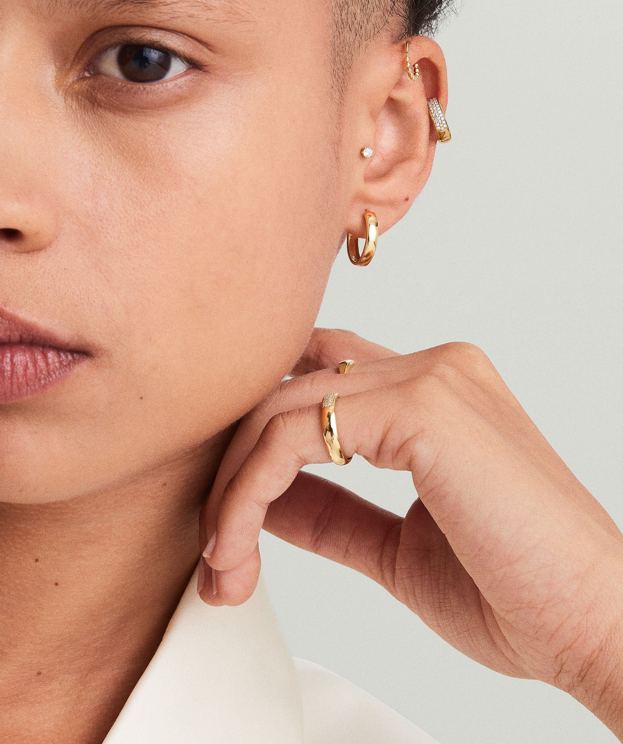 Woman wearing Bold Small Hoops, showcasing their elegant design and perfect size for everyday wear. Close-up focuses on the earring and part of her face.