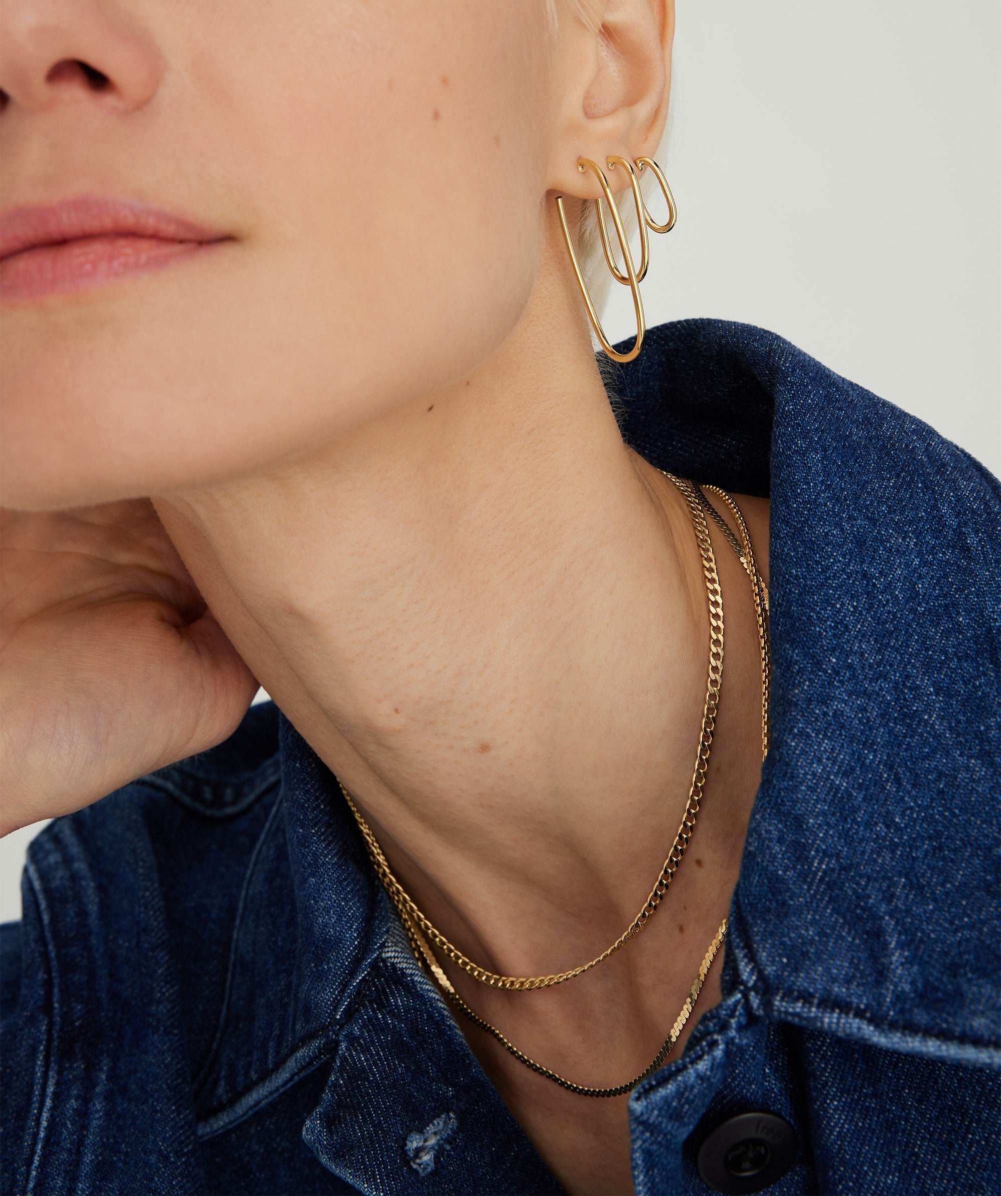 A woman wearing a gold Curb Chain Necklace, showcasing its elegant design and shorter length, ideal for layering with longer necklaces.