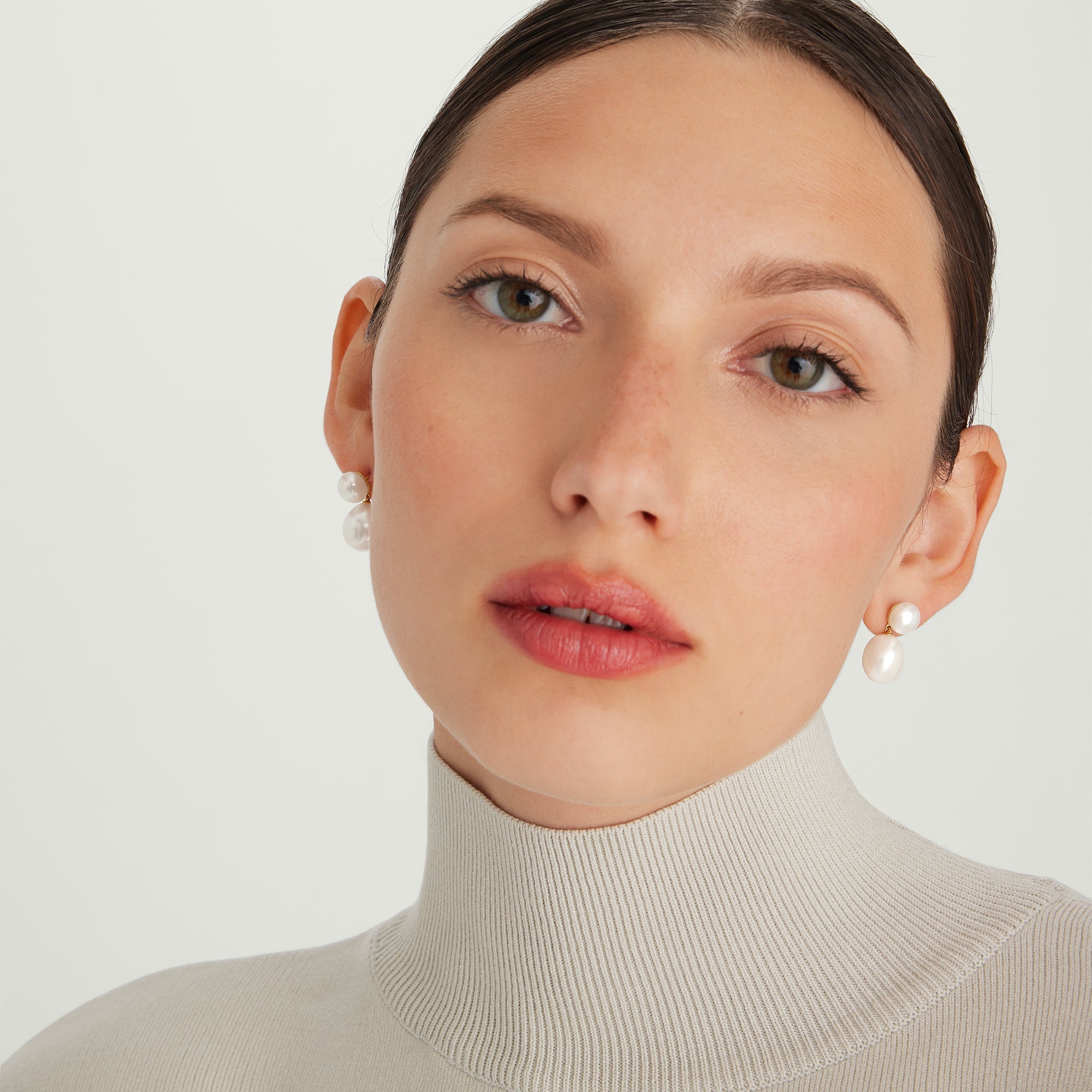 Bold Pearl Drop Earrings showcased on a woman wearing a white turtleneck, featuring elegant pearl drops crafted in 18k gold vermeil with freshwater pearls.