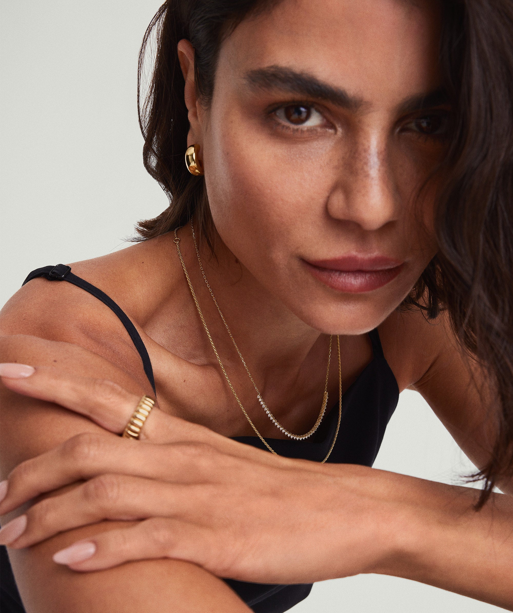 Woman wearing Diamond Half Tennis Necklace, arms crossed, showcasing the brilliance of responsibly sourced diamonds set in 14k solid gold.