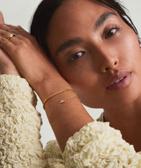 Woman wearing a 14k solid gold Diamond Letter Bracelet with pavÃ© diamond set letters, hands on head, showcasing wedding attire and jewelry.