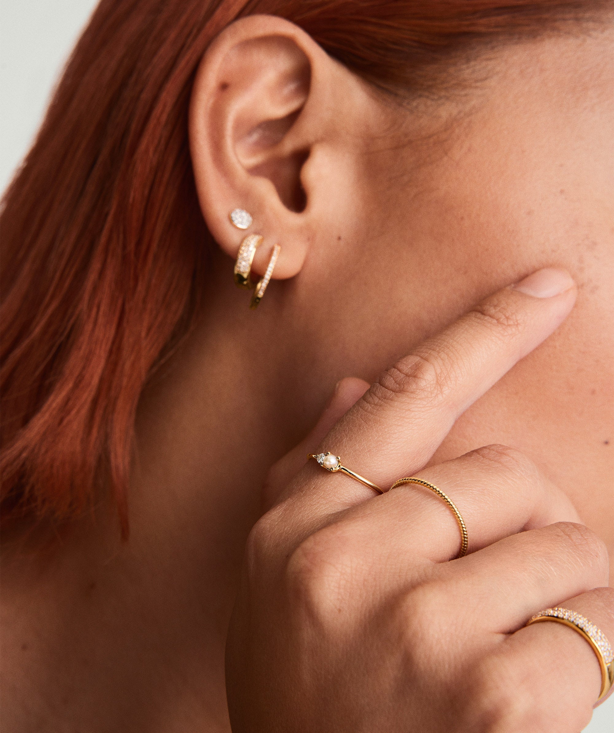 Close-up of a woman's hand wearing a 14k gold Pearl and Diamond Stacker Ring, featuring a freshwater pearl and a responsibly sourced diamond.