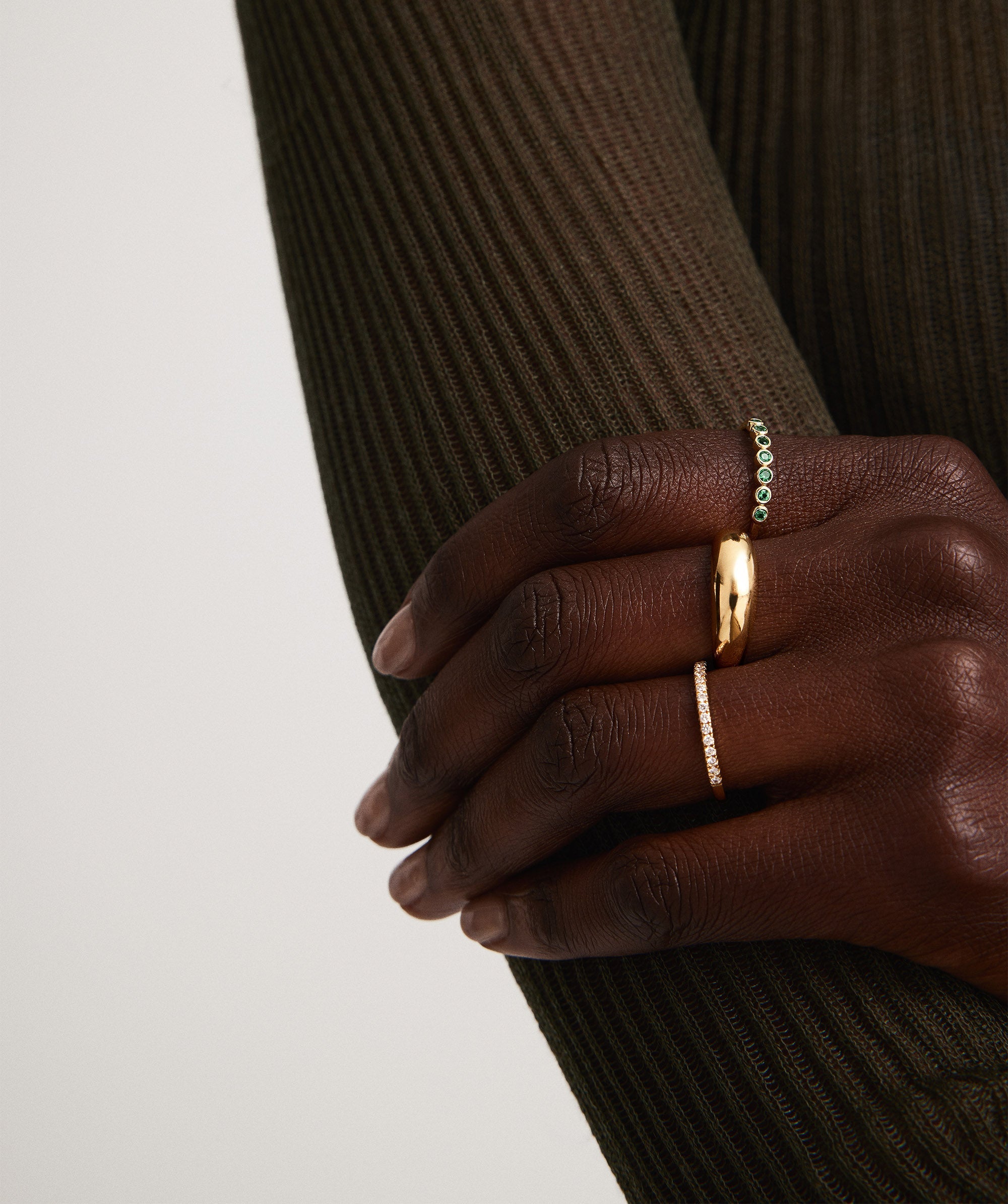 Bezel Emerald Half Eternity Band on hand, featuring bezel-set emeralds on a 14k solid gold band. Handcrafted with unique natural inclusions.