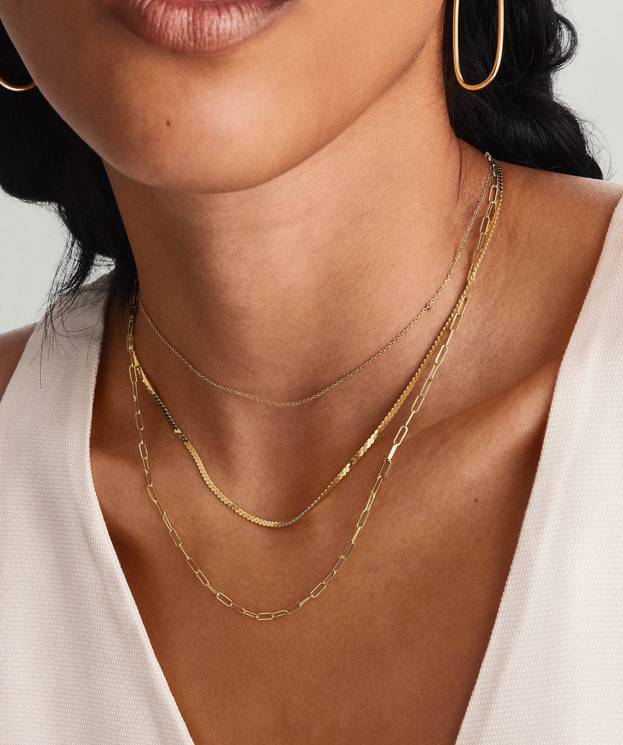 Woman wearing the Serpentine Chain Necklace and matching earrings, showcasing minimalistic gold jewelry suitable for any occasion.