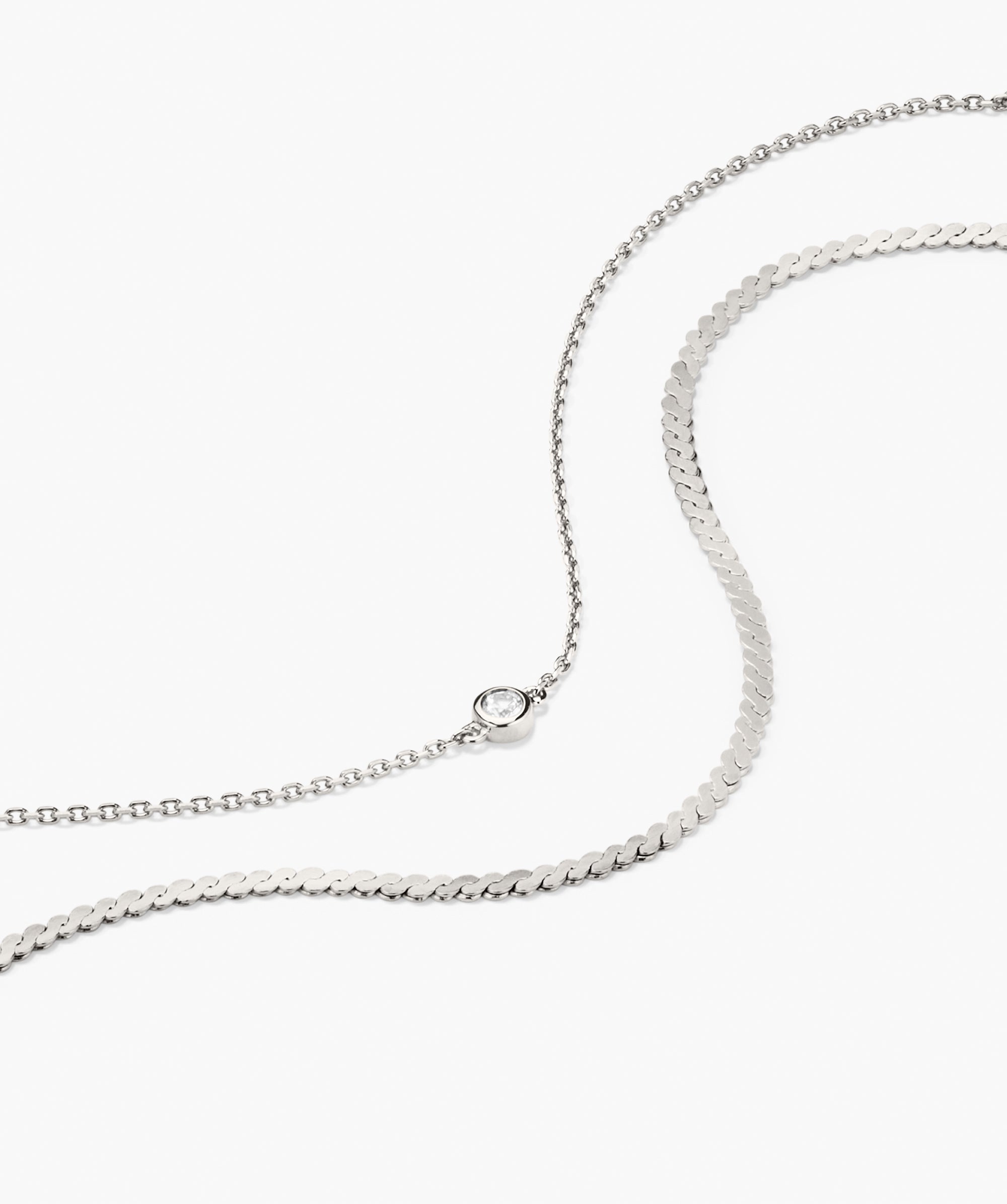 Double Take Bracelet Bundle featuring a fine link chain with a bezel-set clear stone and a wider snake-style chain, both in a delicate silver tone.