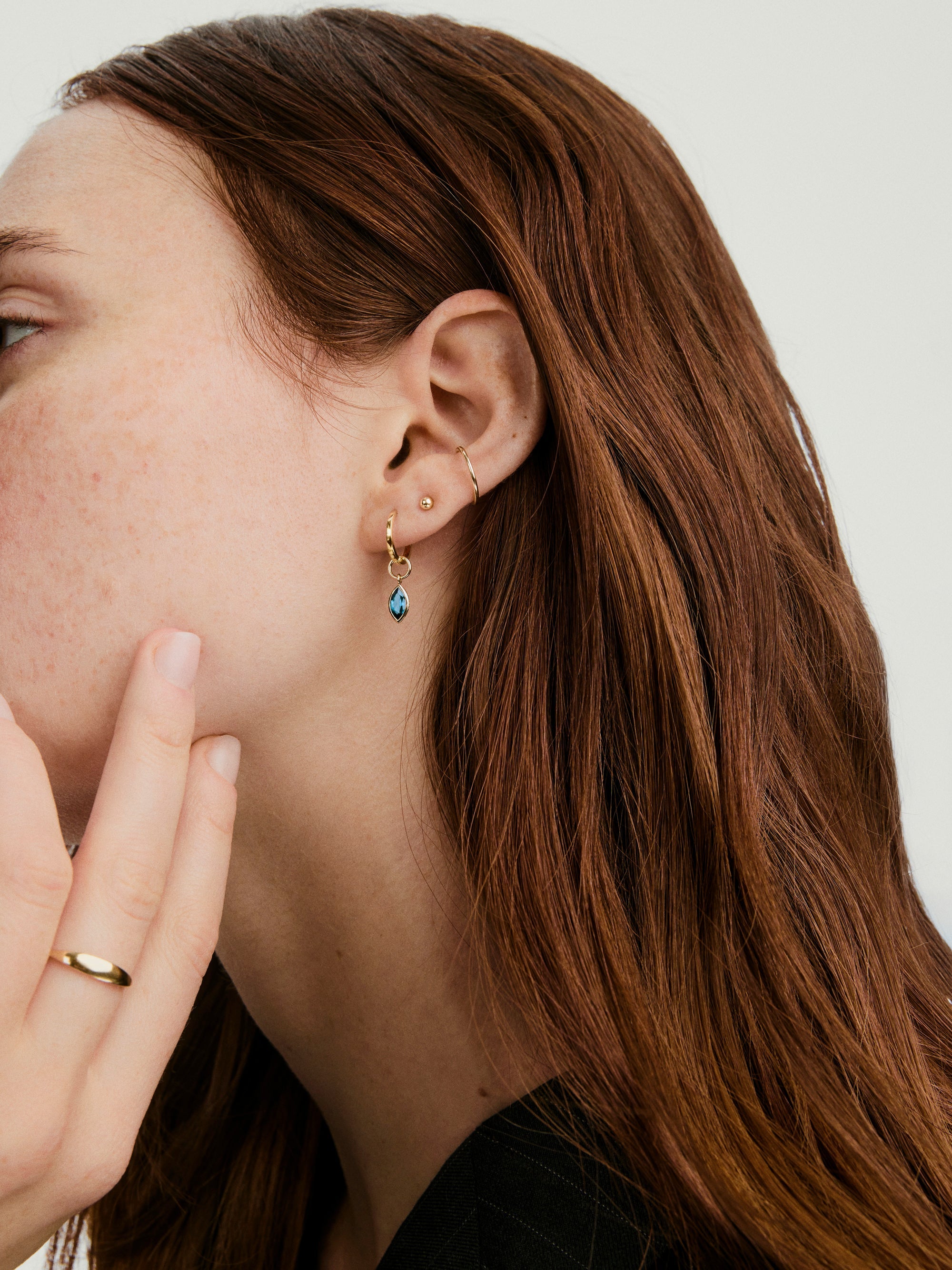 Marquise Gemstone Hoop Charm on woman's finger, highlighting its elegant design. The charm complements hoop earrings like Bold Hoops, adding a sophisticated touch.