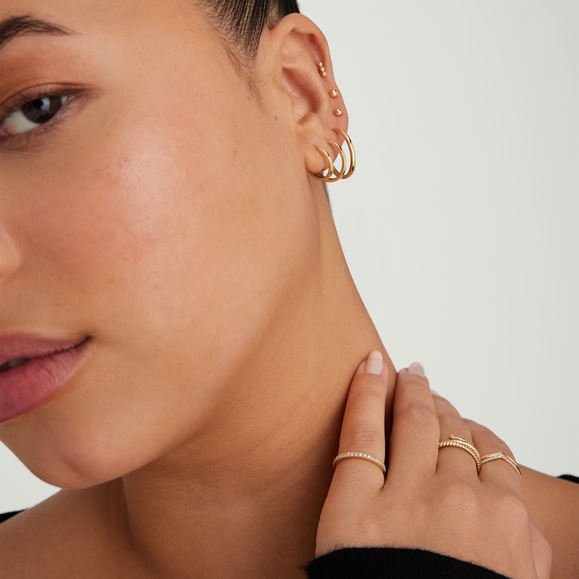 Easy Huggie Hoops: Close-up of a woman's ear wearing gold hoop earrings with a clicker closure, showcasing their effortless, everyday style and comfort.