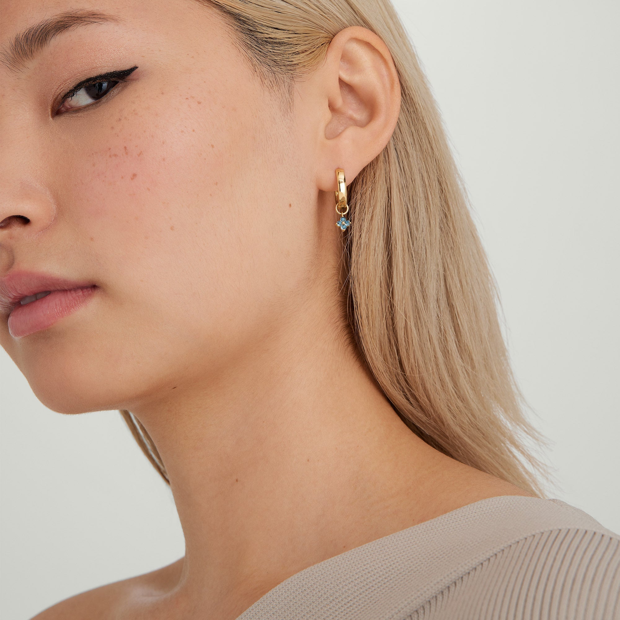 Woman wearing a Single Gemstone Cluster Hoop Charm, showcasing a gold hoop earring with gemstone accents.