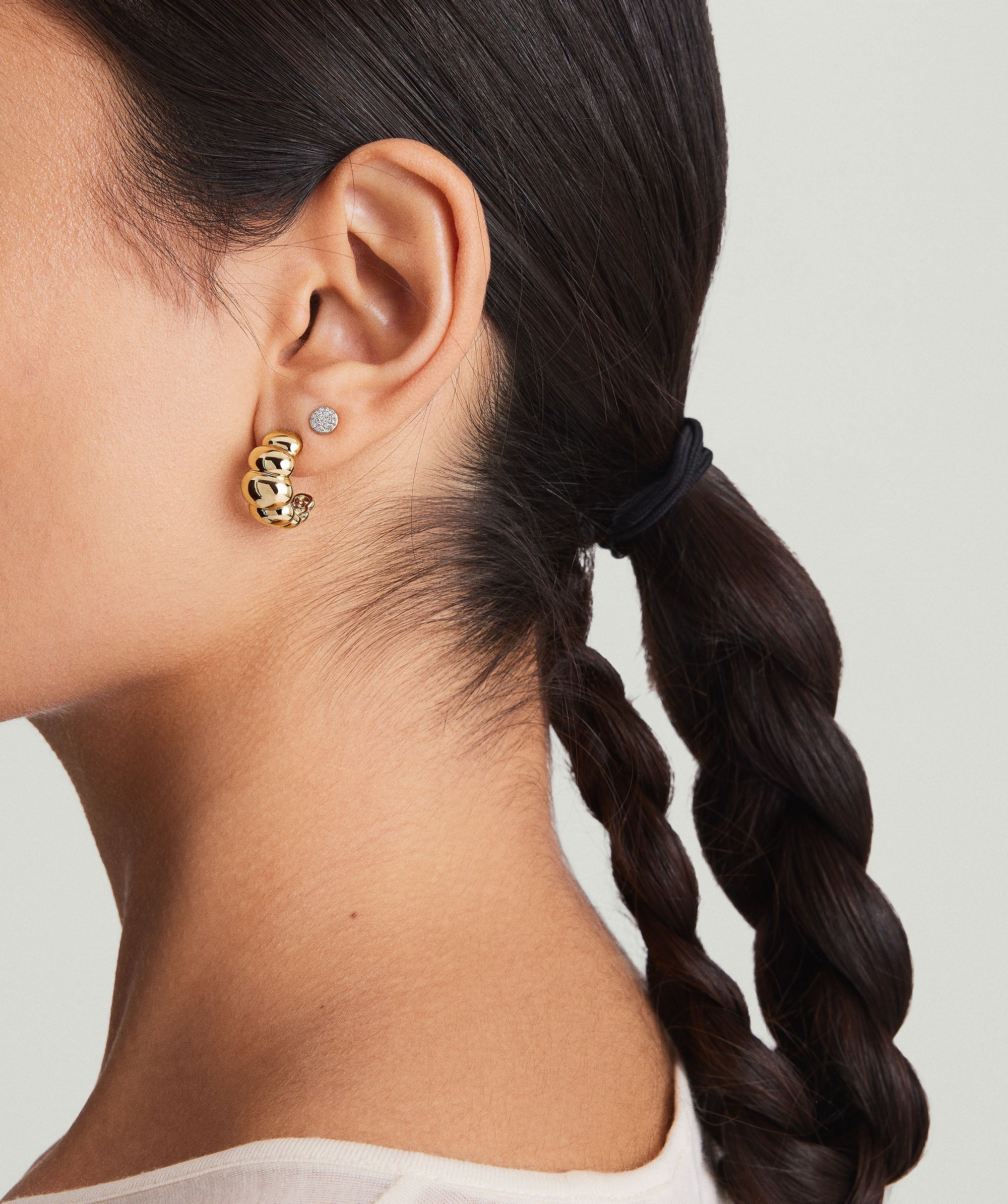Close-up of a woman's ear adorned with Puffy Charlotte Hoops, showcasing bold, fashionable earrings from the Charlotte Collection.