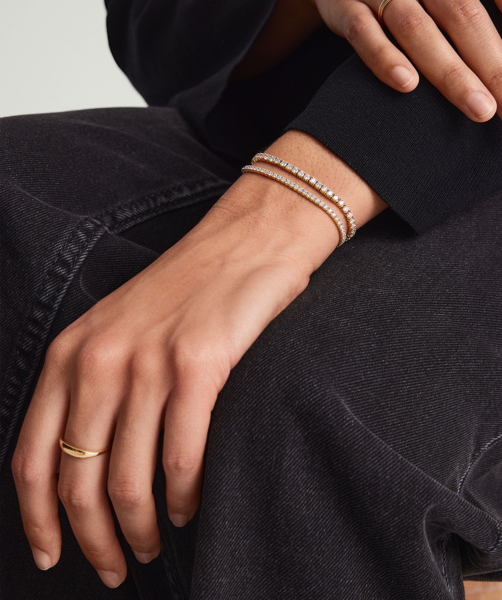 Person wearing a Lab Grown Diamond Tennis Bracelet 1.8mm on their wrist, showcasing the bracelet's gold setting and sparkling diamonds.