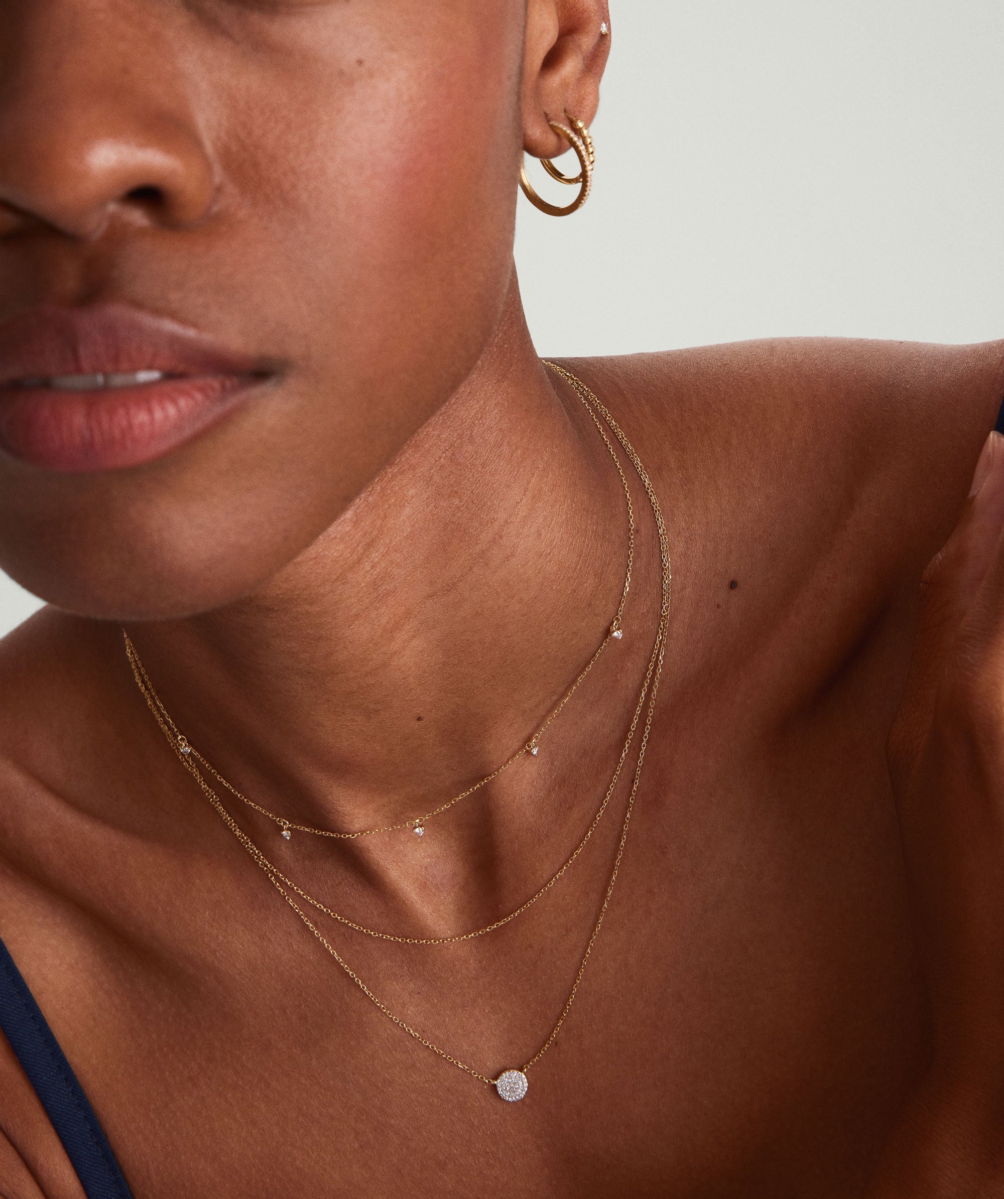 Close-up of a woman wearing the Multi Station Diamond Necklace, featuring five diamonds on a delicate 14k gold choker.