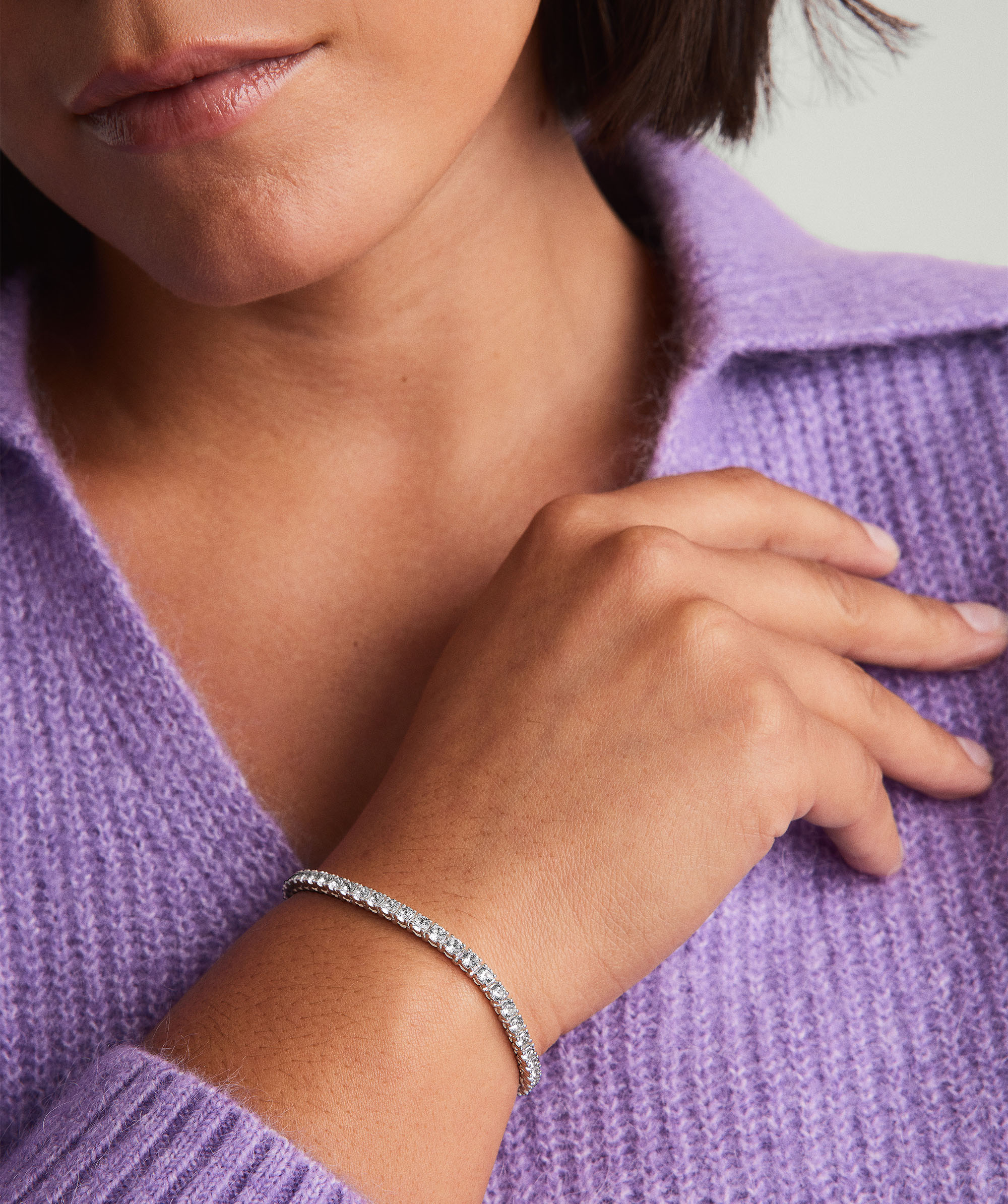 Close-up of a person wearing a Lab Grown Sapphire Tennis Bracelet, featuring a single row of sparkling gems set in sterling silver on their wrist.