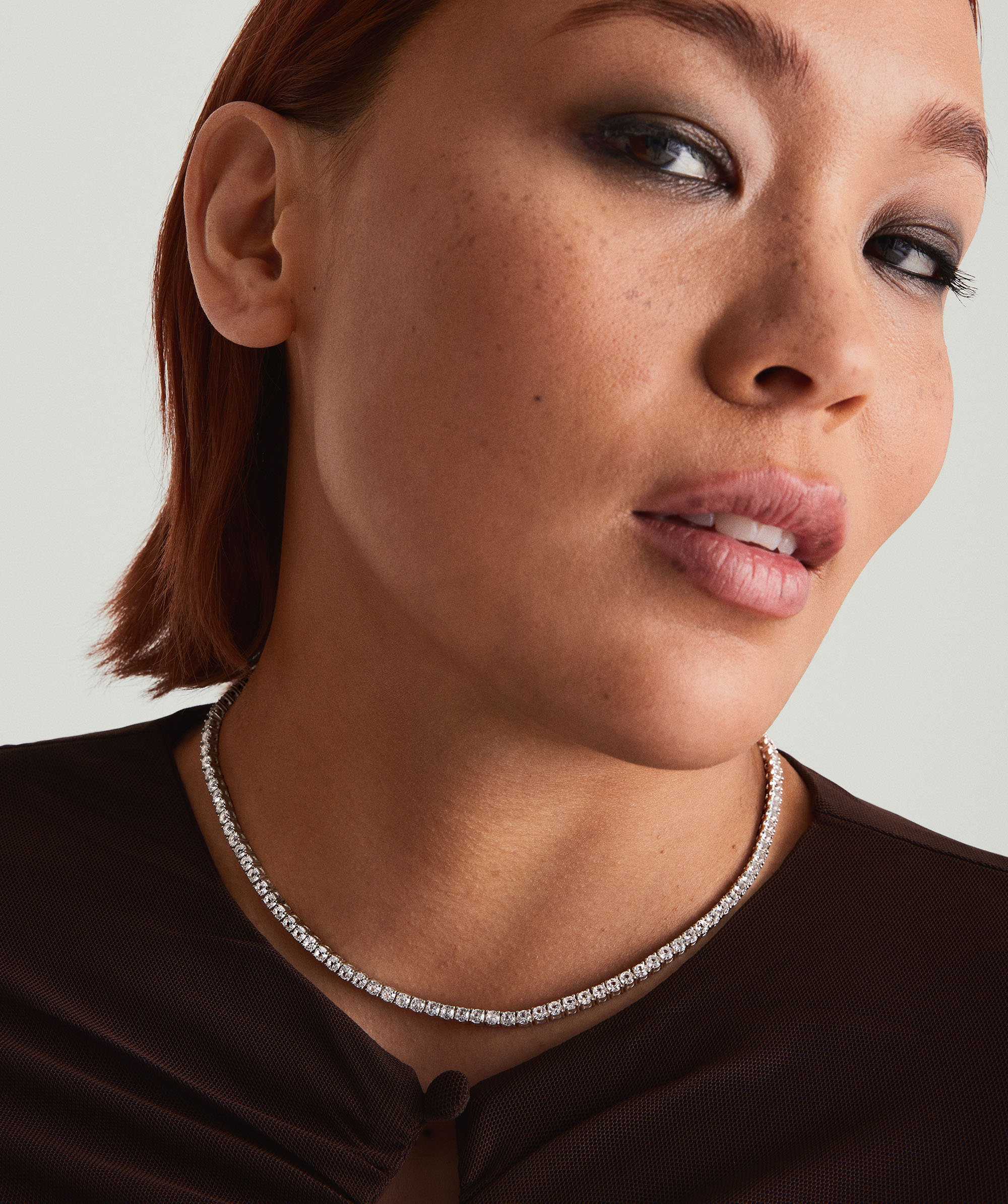 Woman wearing the Lab Grown Sapphire Tennis Necklace, featuring sparkling lab-grown sapphires set in sterling silver, captured in a close-up portrait.