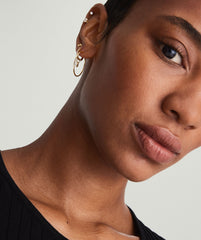 Close-up of a woman wearing handcrafted large gold hoop earrings.