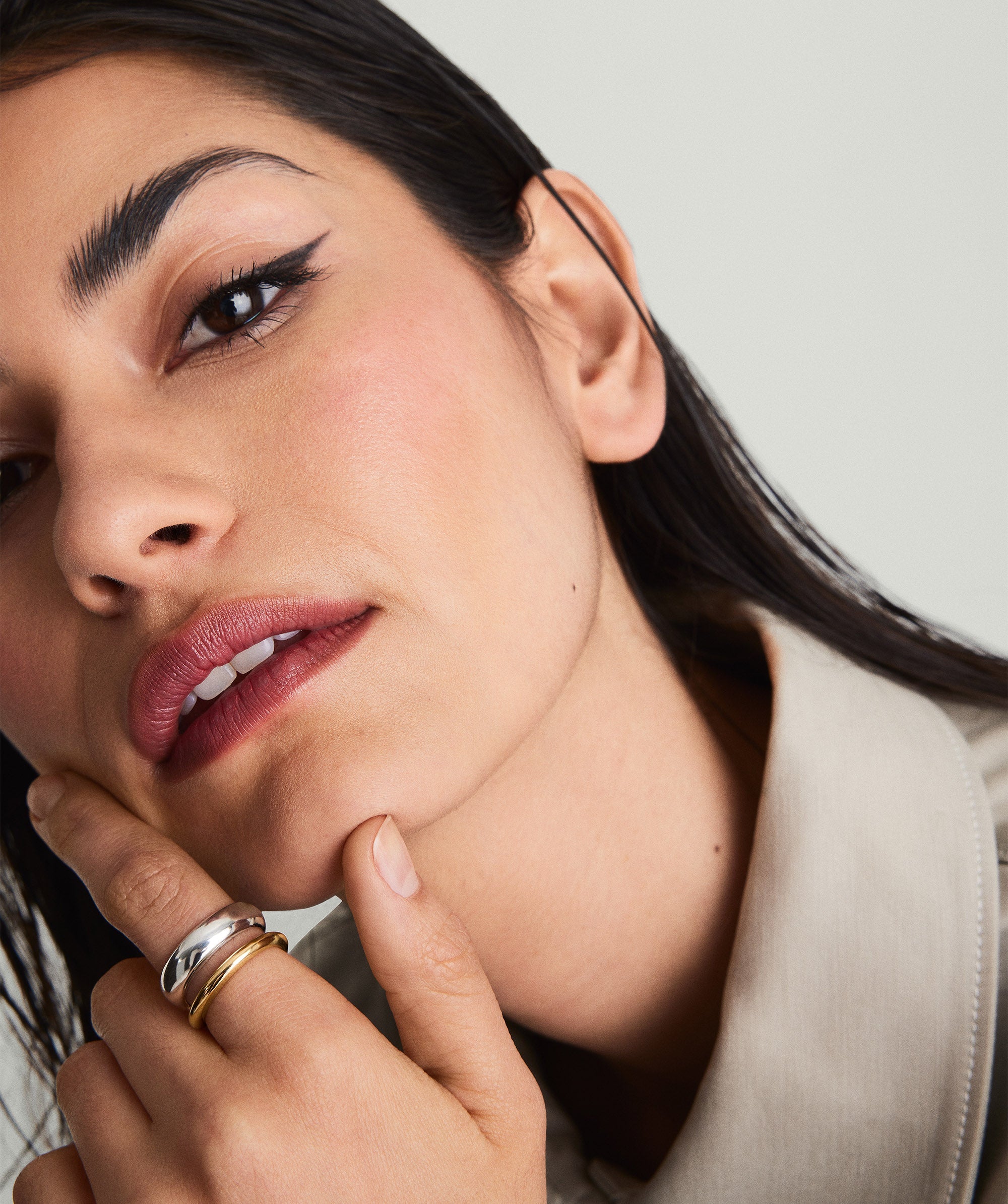 Woman with hand on chin showcasing the Duet Mixed Ring, featuring mixed metals in two widths, handcrafted in 18k gold vermeil and sterling silver.