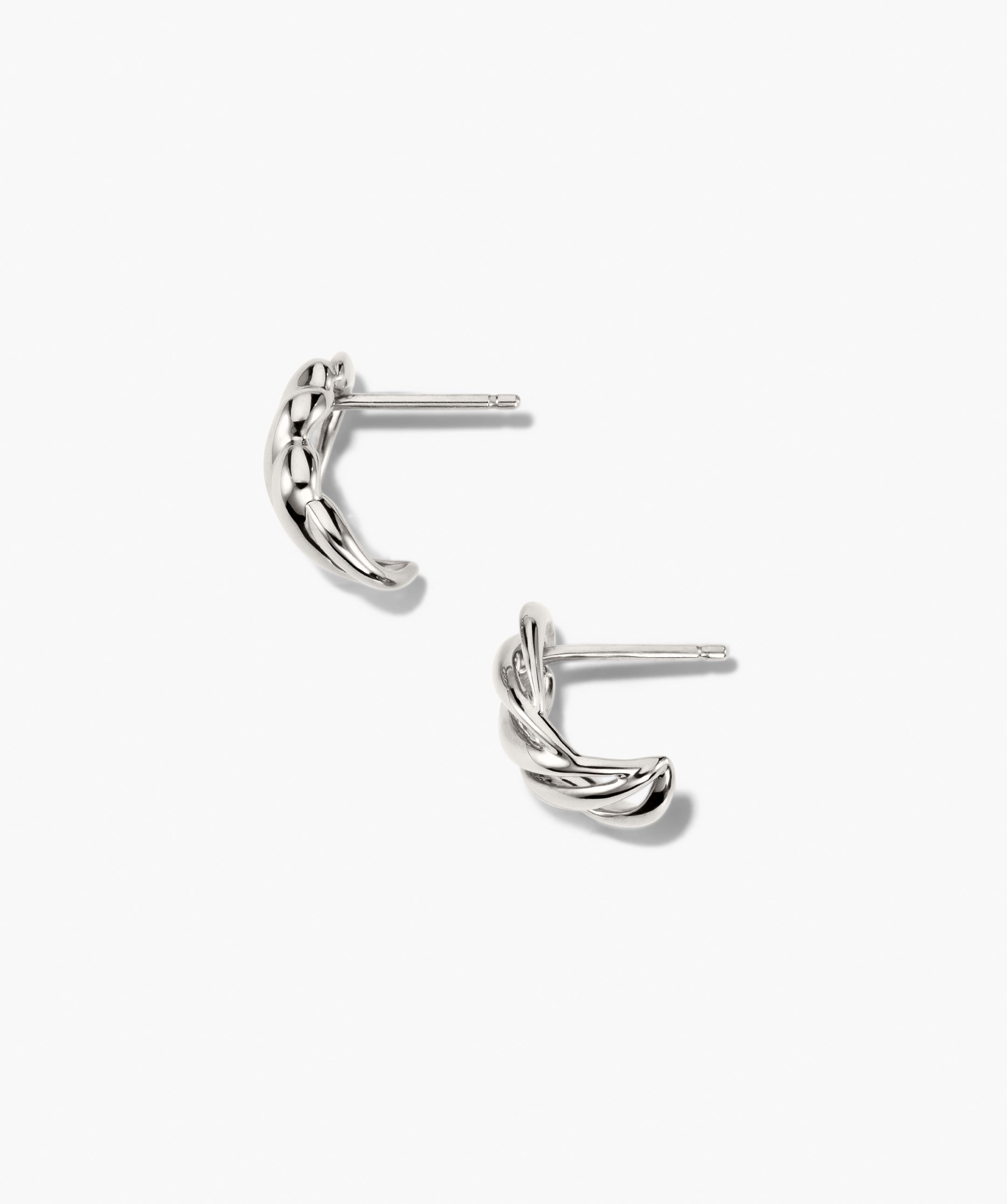 Bold Open DÃ´me Huggies featuring silver-tone, twisted hoop design with textured, intertwined rope appearance; asymmetrical, eye-catching, and understated earrings with short posts for piercing.