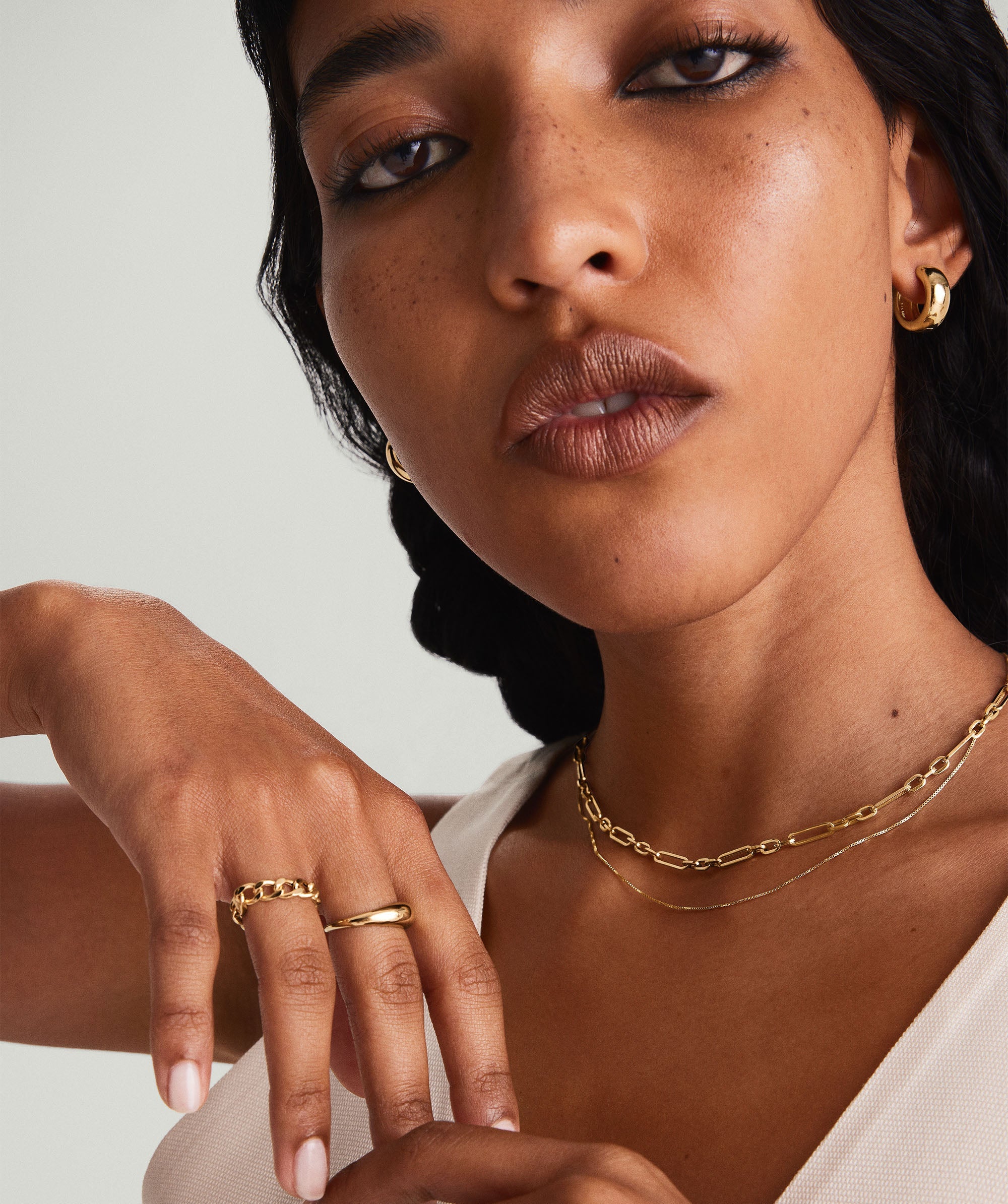 A woman wearing the Triple Link Paperclip Chain Charm Necklace, showcasing its intricate 14k gold links and elegant design, posed closely for the camera.