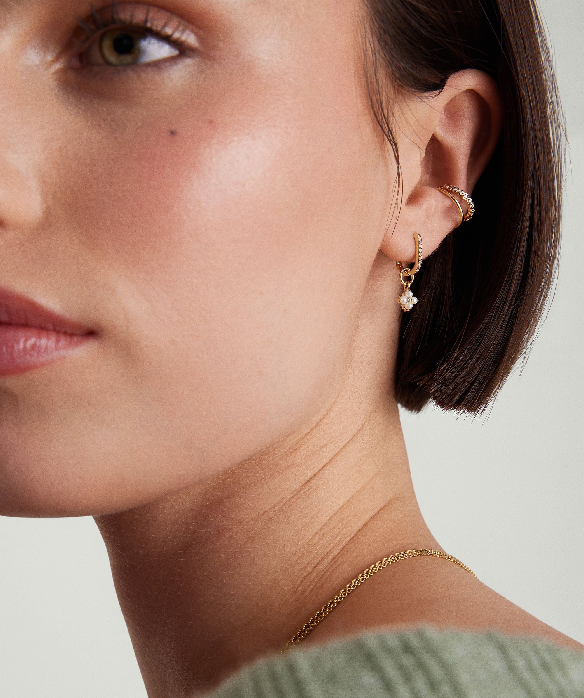 Cluster Pearl Hoop Charm: Close-up of a woman's ear showcasing a 14k gold hoop earring adorned with a cluster of freshwater pearls.