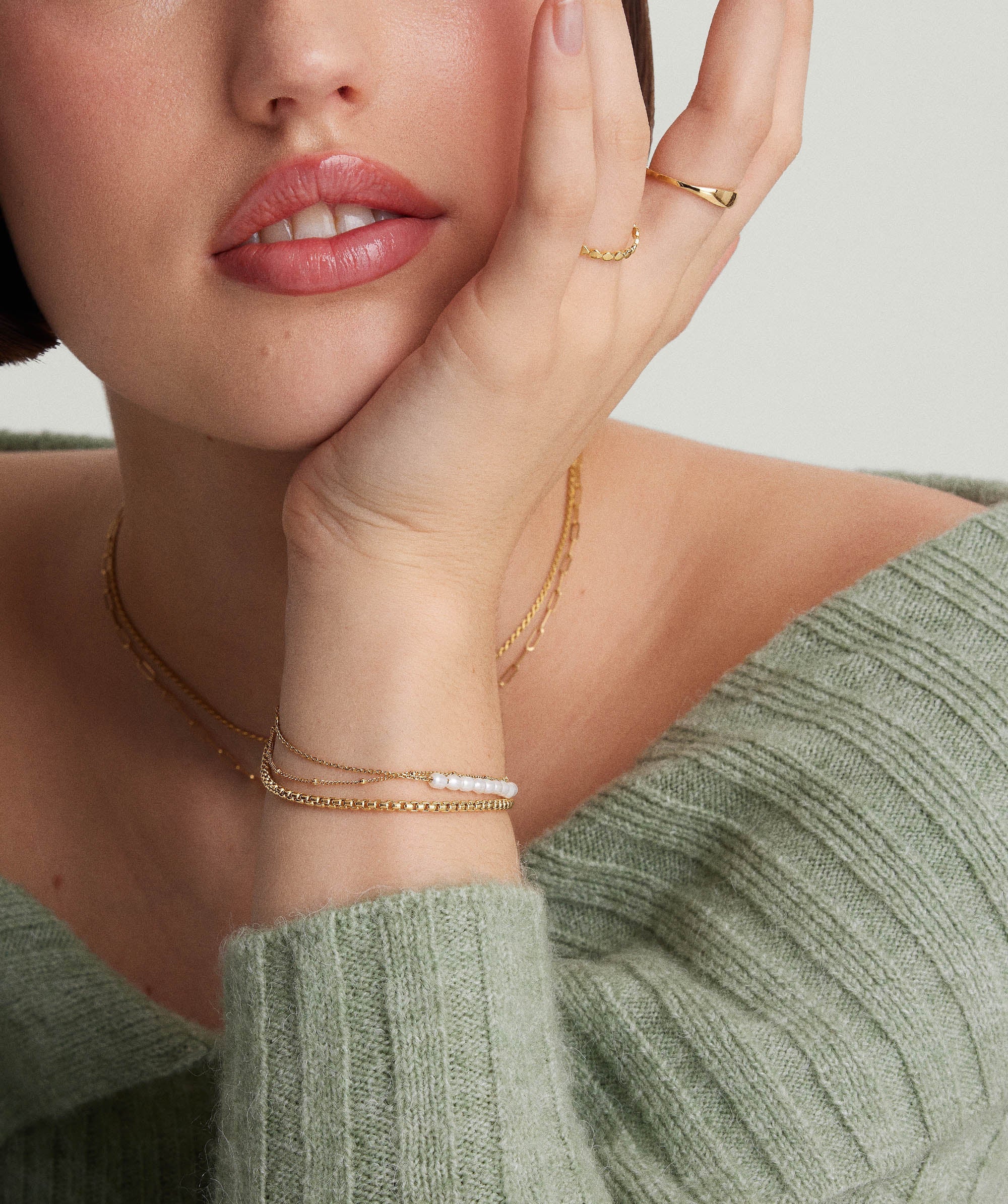 Close-up of a woman wearing a Tiny Pearl Bracelet, highlighting the delicate pearls and gold chain on her wrist.