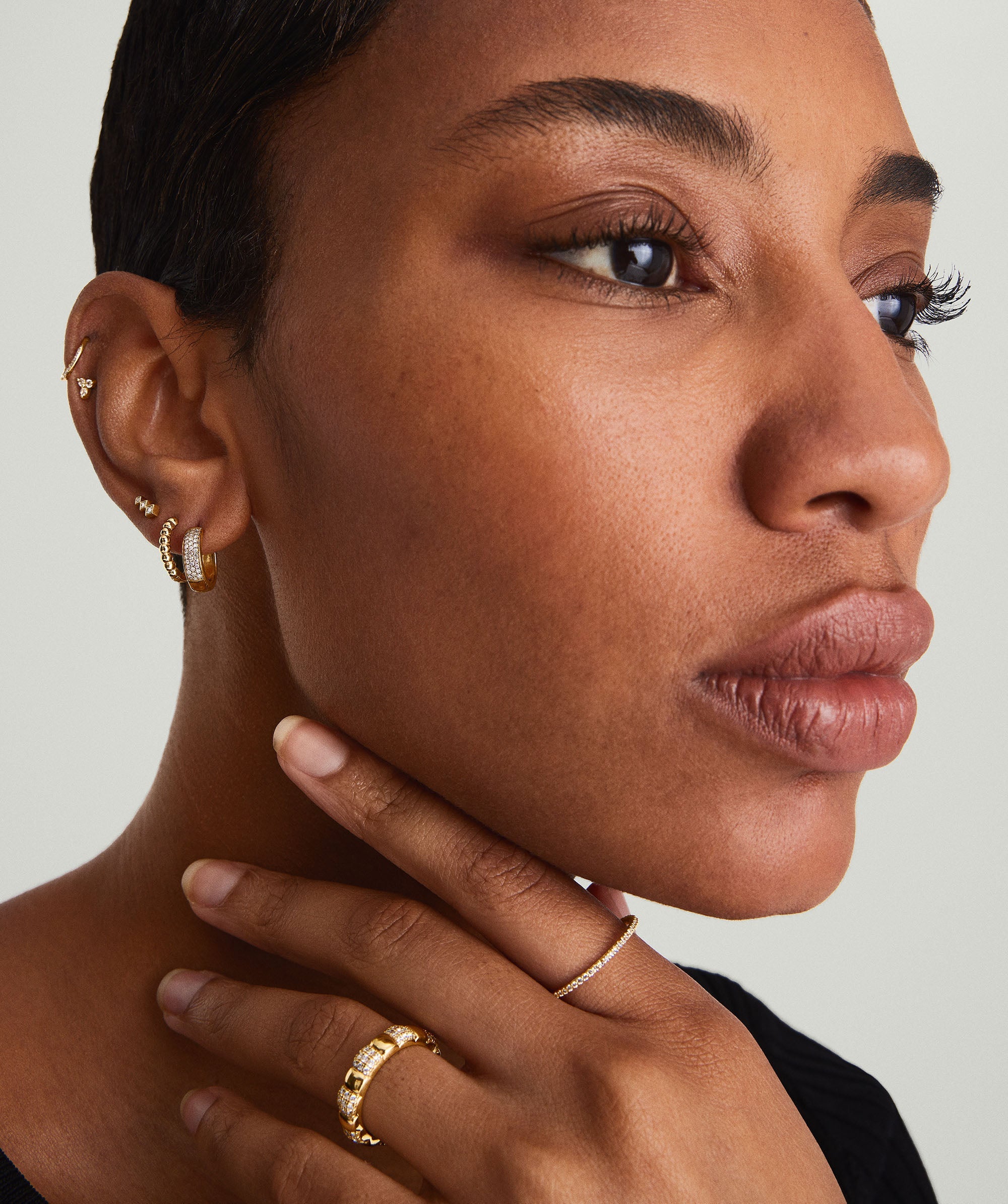 Woman wearing Bold PavÃ© Diamond Huggie Hoops, showcasing intricate 14k gold design with responsibly sourced diamonds.