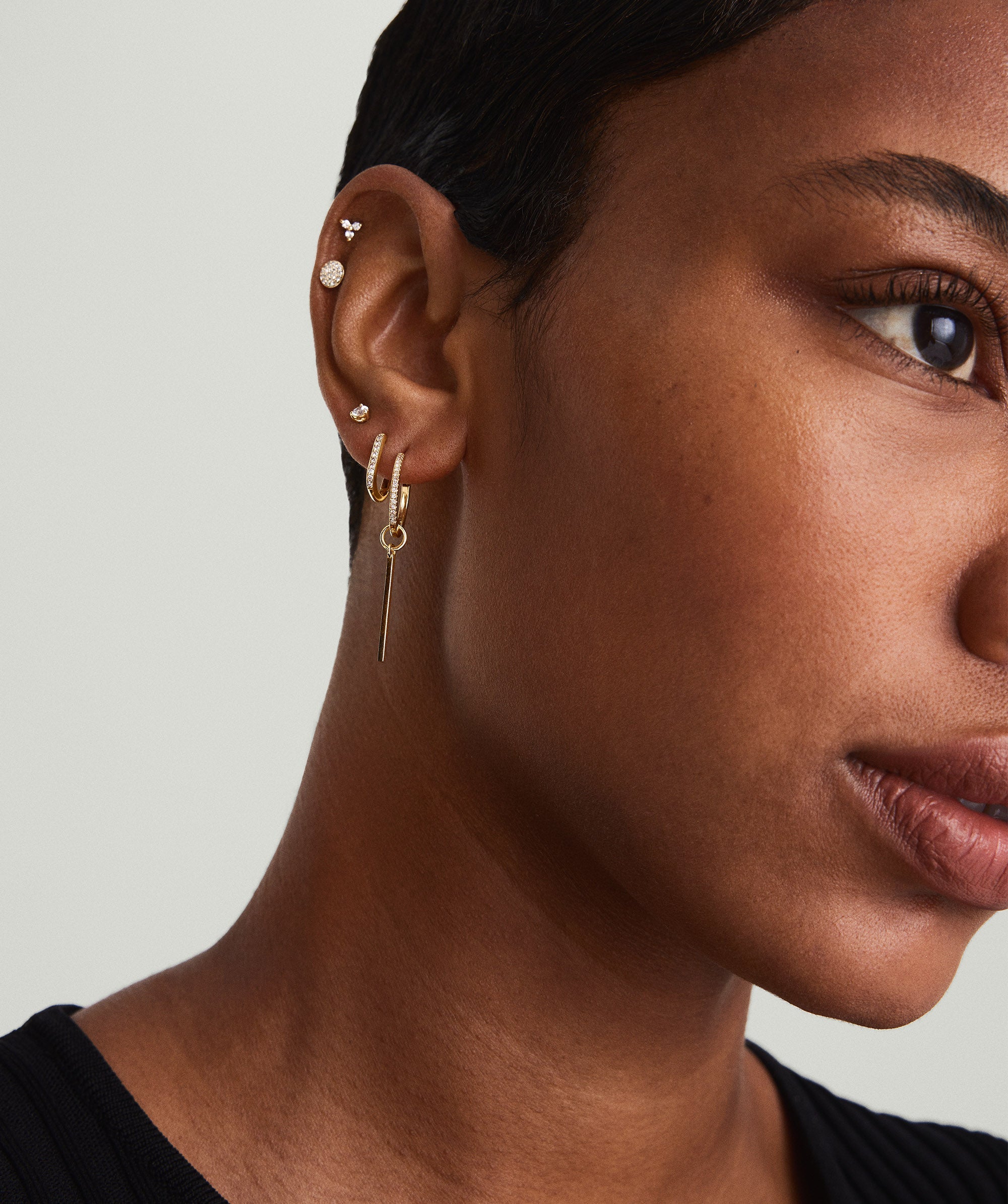PavÃ© Diamond Small Hoops on a woman's ear, showcasing handcrafted 14k solid gold hoops with pavÃ© diamond detailing.