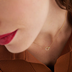 Close-up of a woman wearing a PavÃ© Diamond Linked Necklace with two interlinked rings, featuring diamonds and handcrafted in 14k gold.