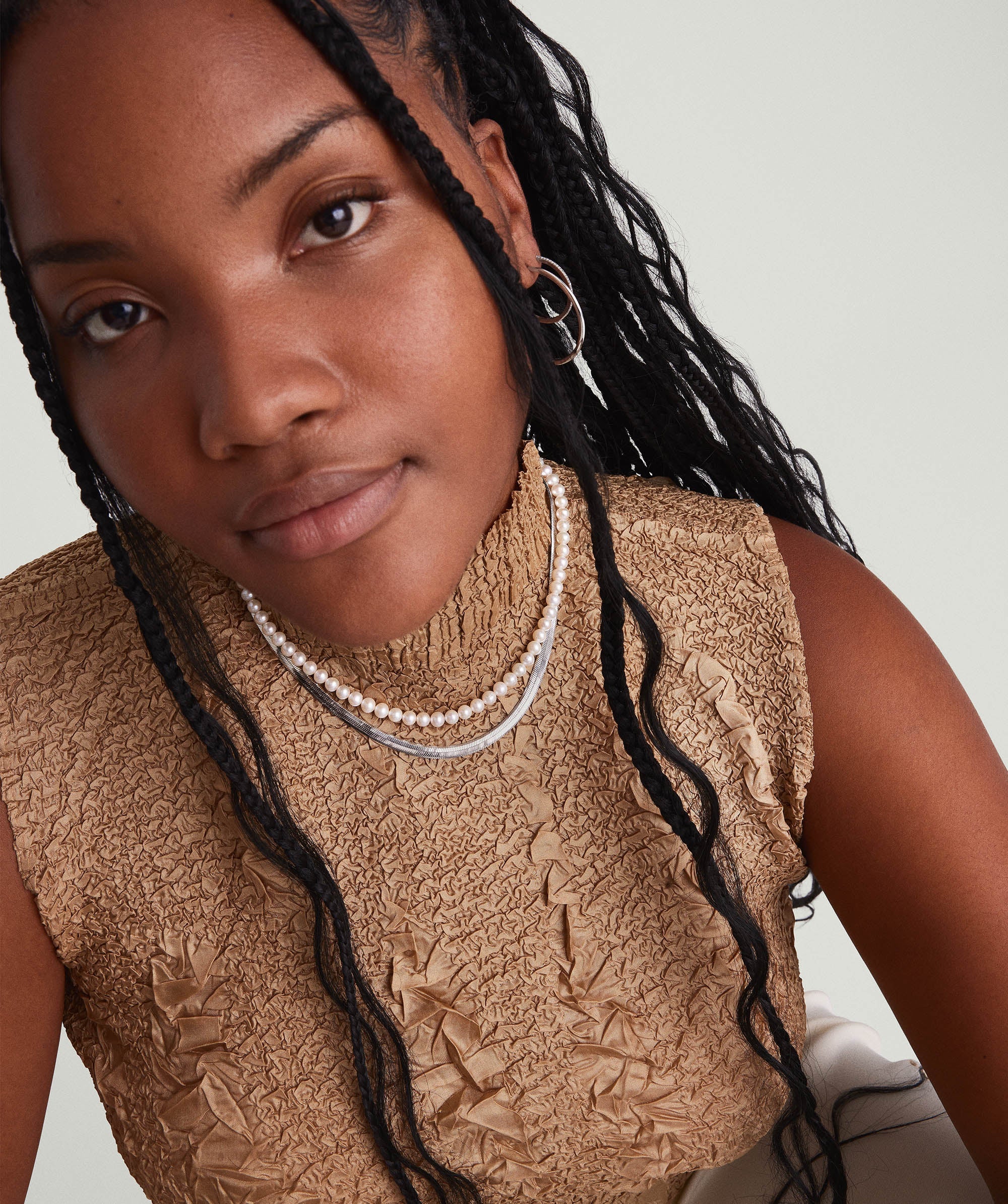 Paradigm Pearl Necklace worn by a woman with braided hair, featuring handcrafted freshwater pearls and a sterling silver clasp.