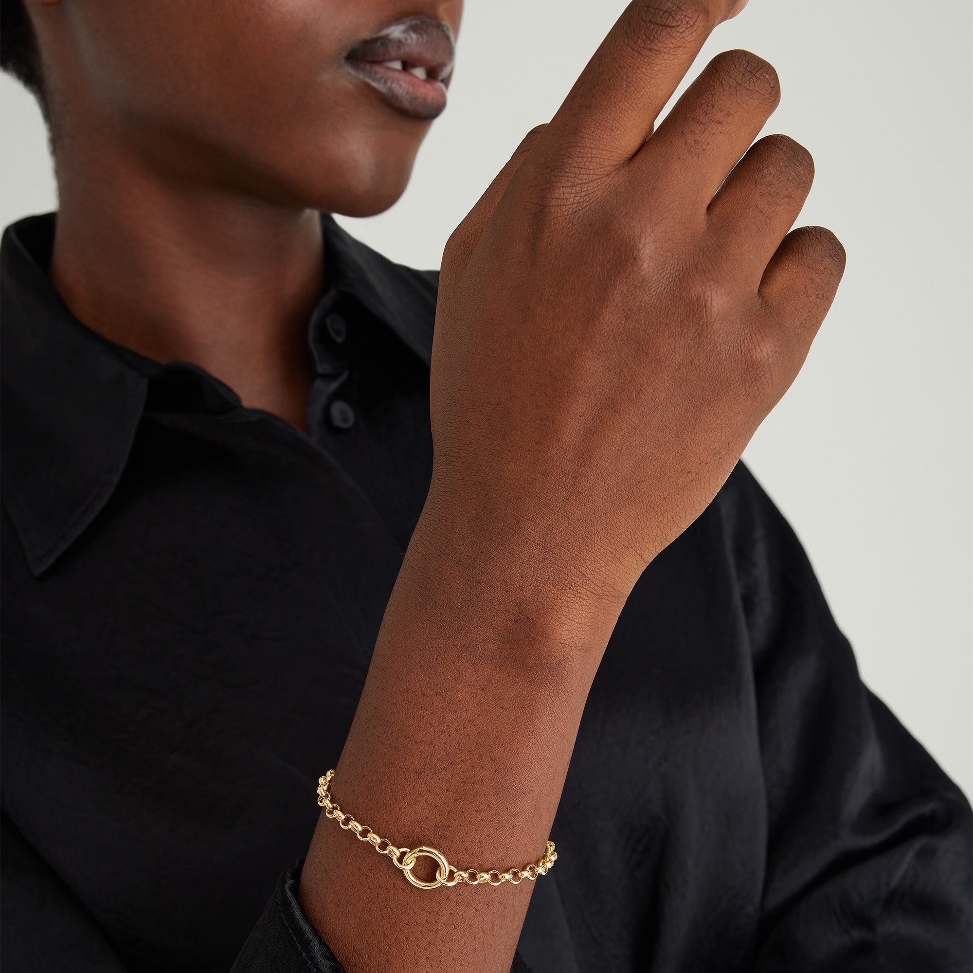 Woman wearing a black shirt, showcasing the Rolo Chain Charm Bracelet in 14k solid gold, with a close-up of the bracelet's Stacker Clasp.