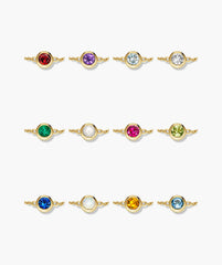 Sia Birthstone Bracelet features twelve bezel-set gemstones on gold chains, offering personalized elegance with vibrant stones like garnet, amethyst, and sapphire. Ideal for gifting or personal wear.