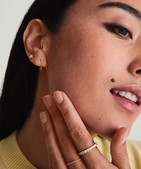 Single Diamond Trio Chain Stud worn by a woman, showcasing a 14k gold earring with three diamonds and a chain connecting two piercings.